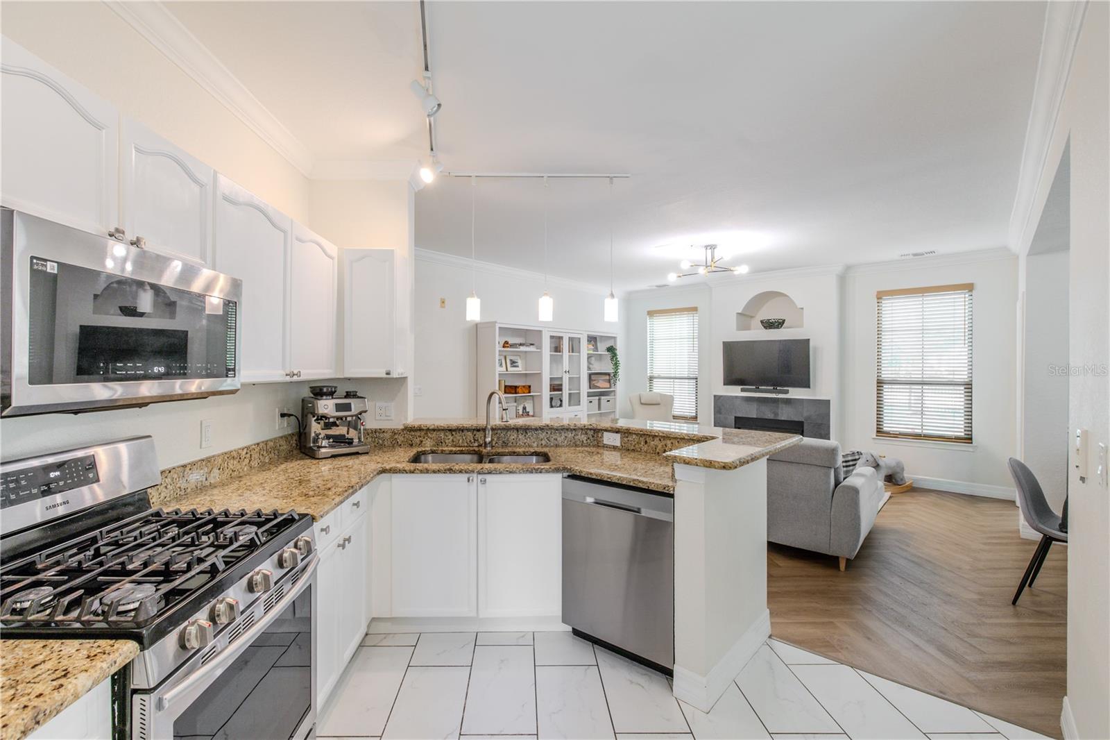 Raised-panel cabinetry wraps the space, creating a bright, cohesive look, while warm granite countertops provide generous prep and serving areas.