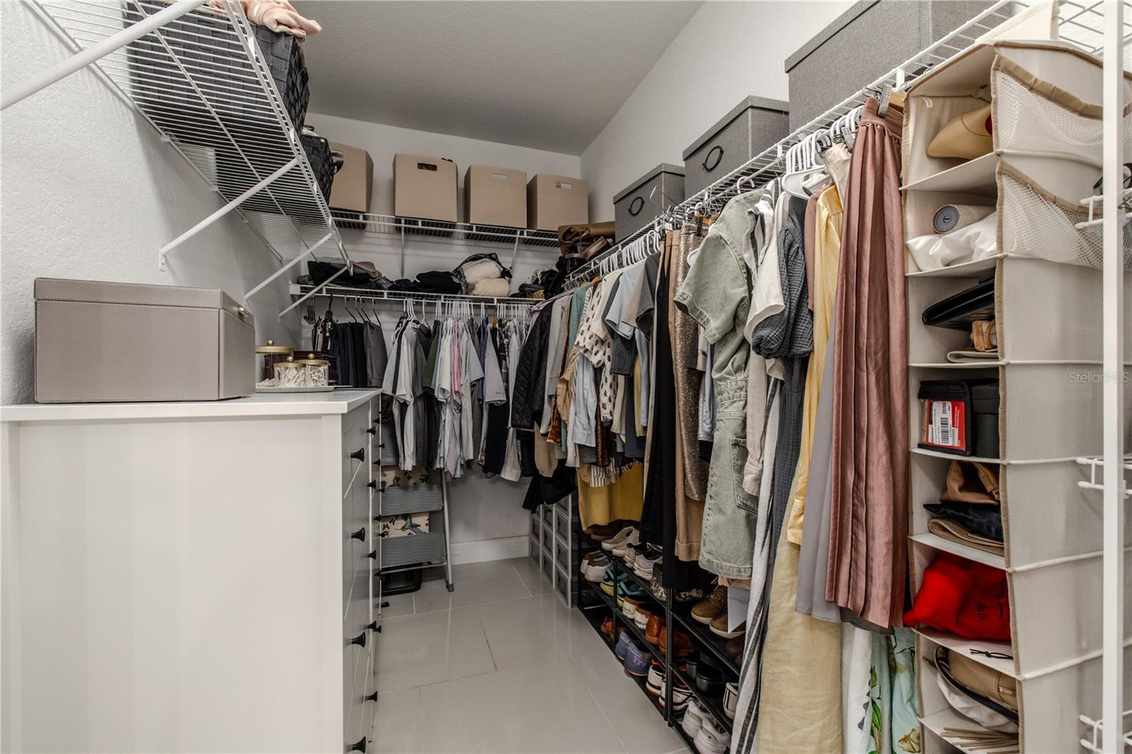 The primary bedroom walk-in closet is thoughtfully designed for both organization and functionality, featuring a wraparound layout with double hanging rods, multiple wire shelves, and ample storage from floor to ceiling.