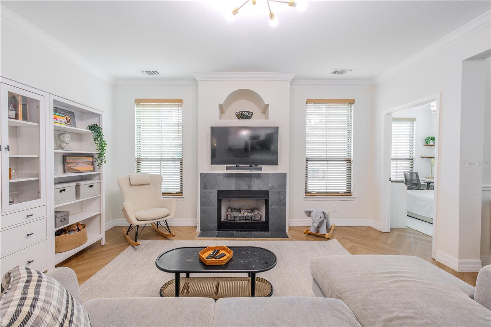 A modern fireplace anchors the room, framed by a tiled surround and an architectural niche above, providing a natural focal point without overwhelming the space.