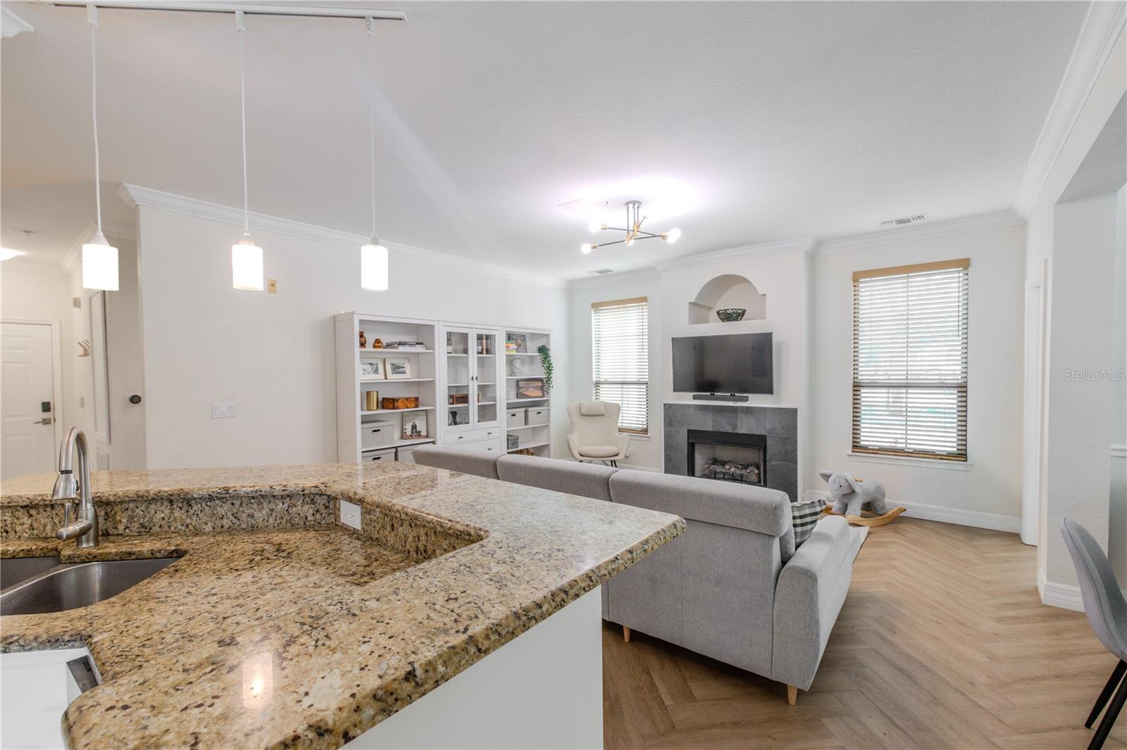 This open-concept kitchen with granite peninsula overlookis the living area, showcasing seamless flow, warm finishes, and abundant natural light.