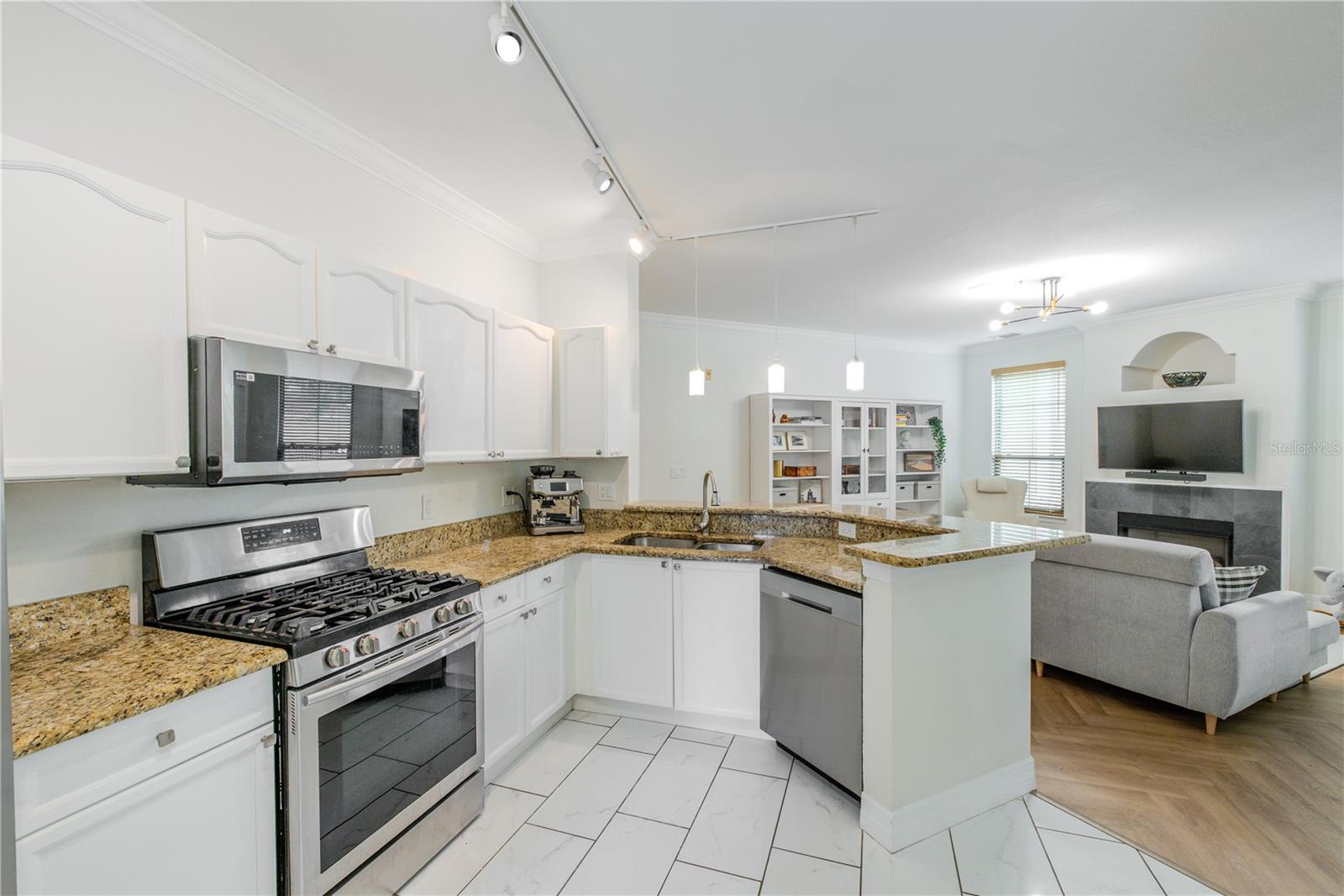 Raised-panel cabinetry provides ample storage and a clean, timeless look, complemented by warm granite countertops that add contrast and durability. Stainless steel appliances—including a gas range, built-in microwave, and dishwasher—offer everyday convenience and a cohesive finish.