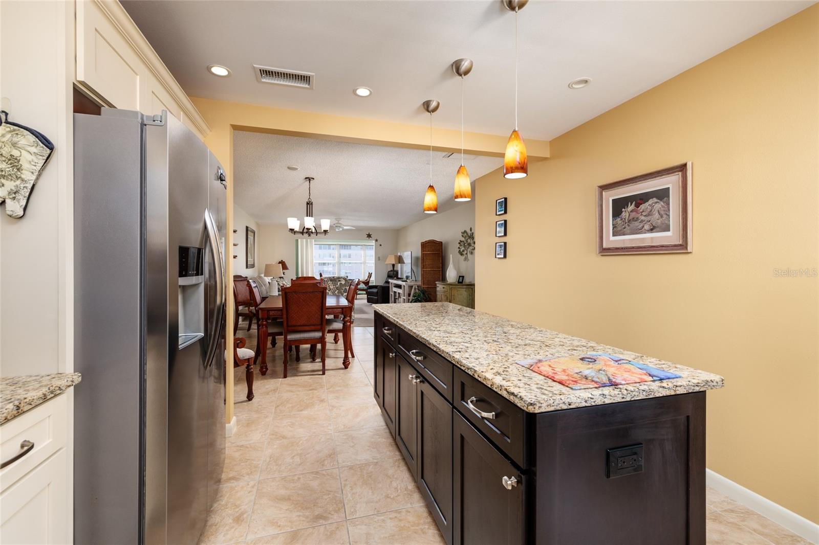 Kitchen island with cabinets. drawers and an electrical outlet. Porcelain tile flooring. Open floor plan.