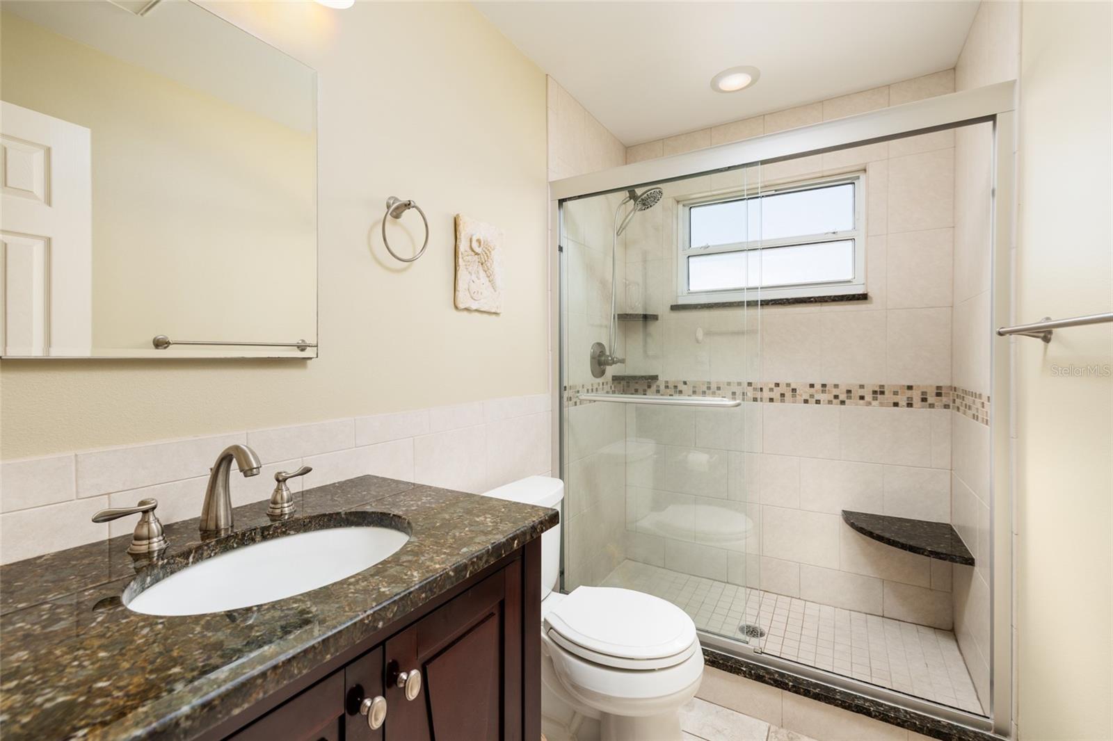 Primary bathroom (updated) w/exhaust fan, GFCI outlet & shower w/bench. Hurricane impact window.