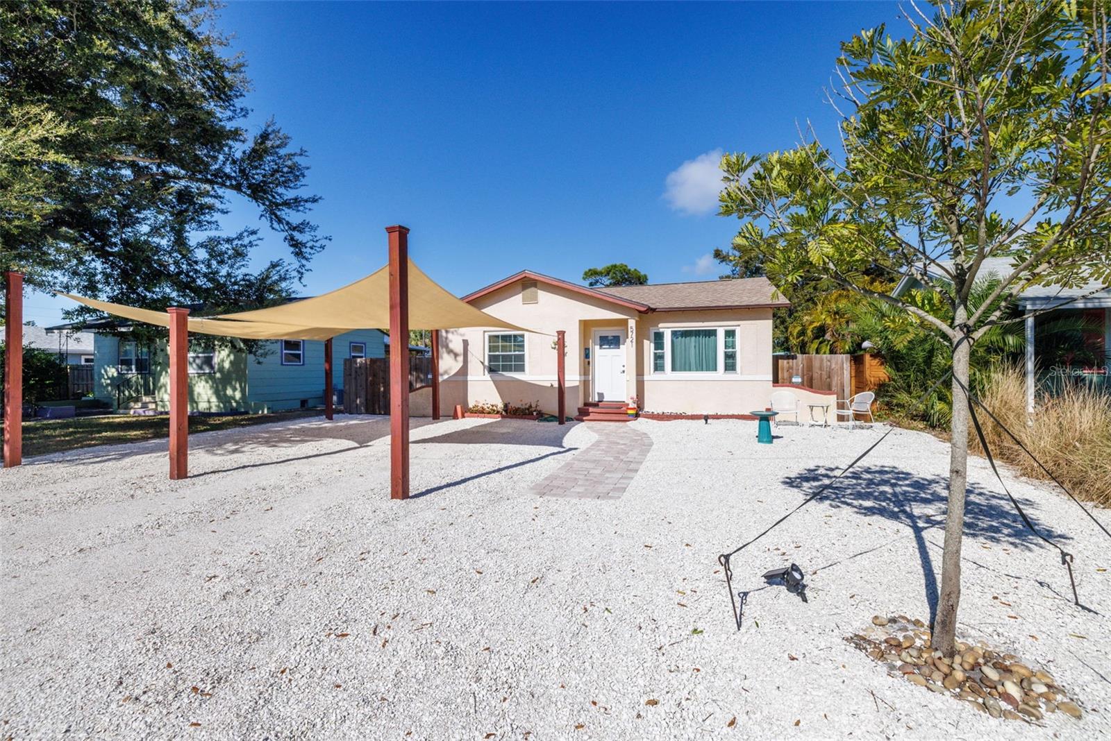 1952 charming bungalow home represents classic mid-century modern Florida residential architecture, now modernized with contemporary finishes with sun sails for shade and parking several cars up front .