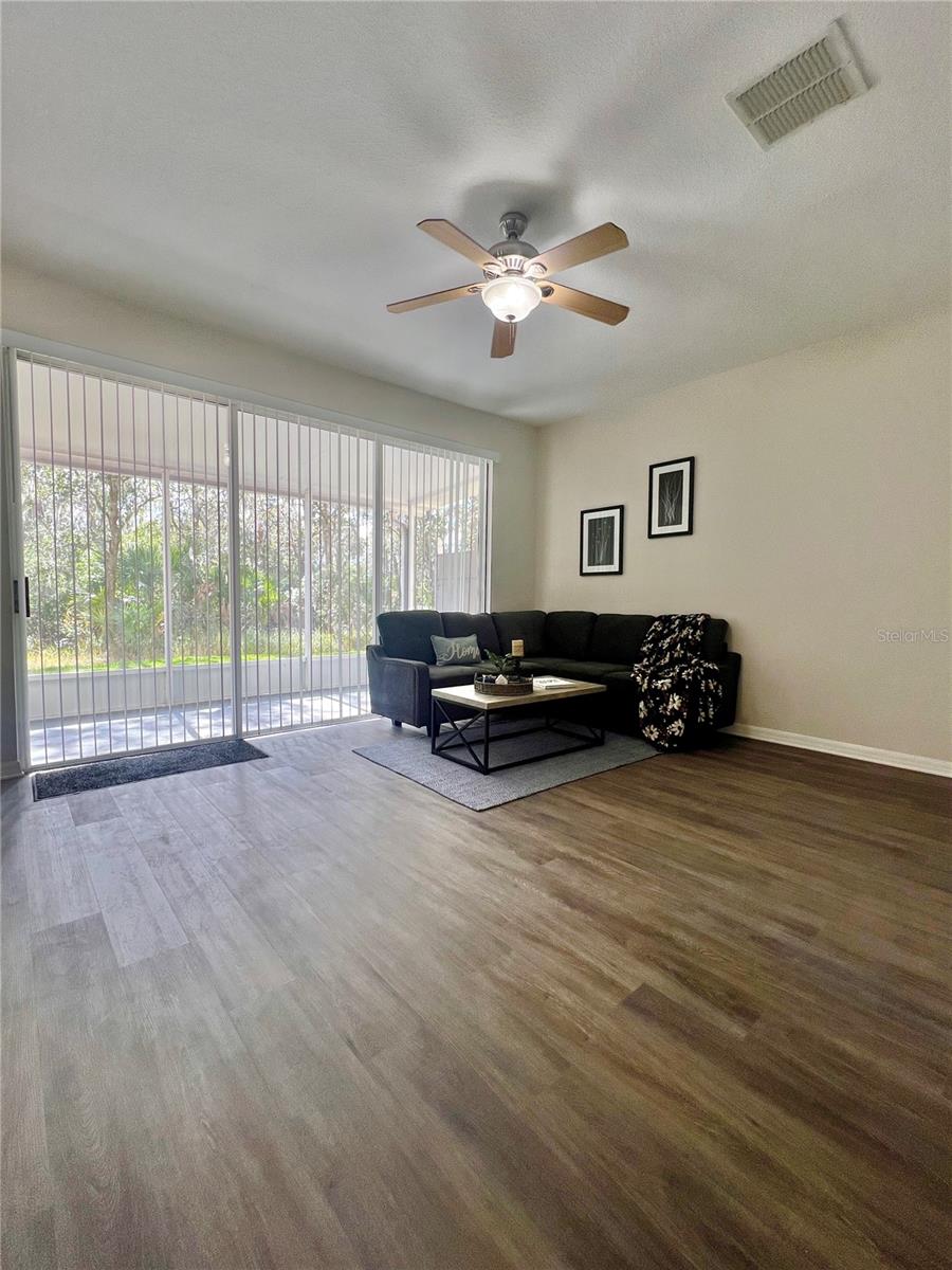 The triple slider allows natural light to pour in.  The ceiling fan has two optional color of blades.  Luxury vinyl plank flooring covers the first floor.