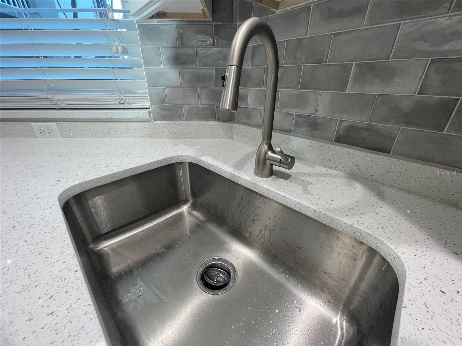 Big stainless sink is deep and has a pull down faucet