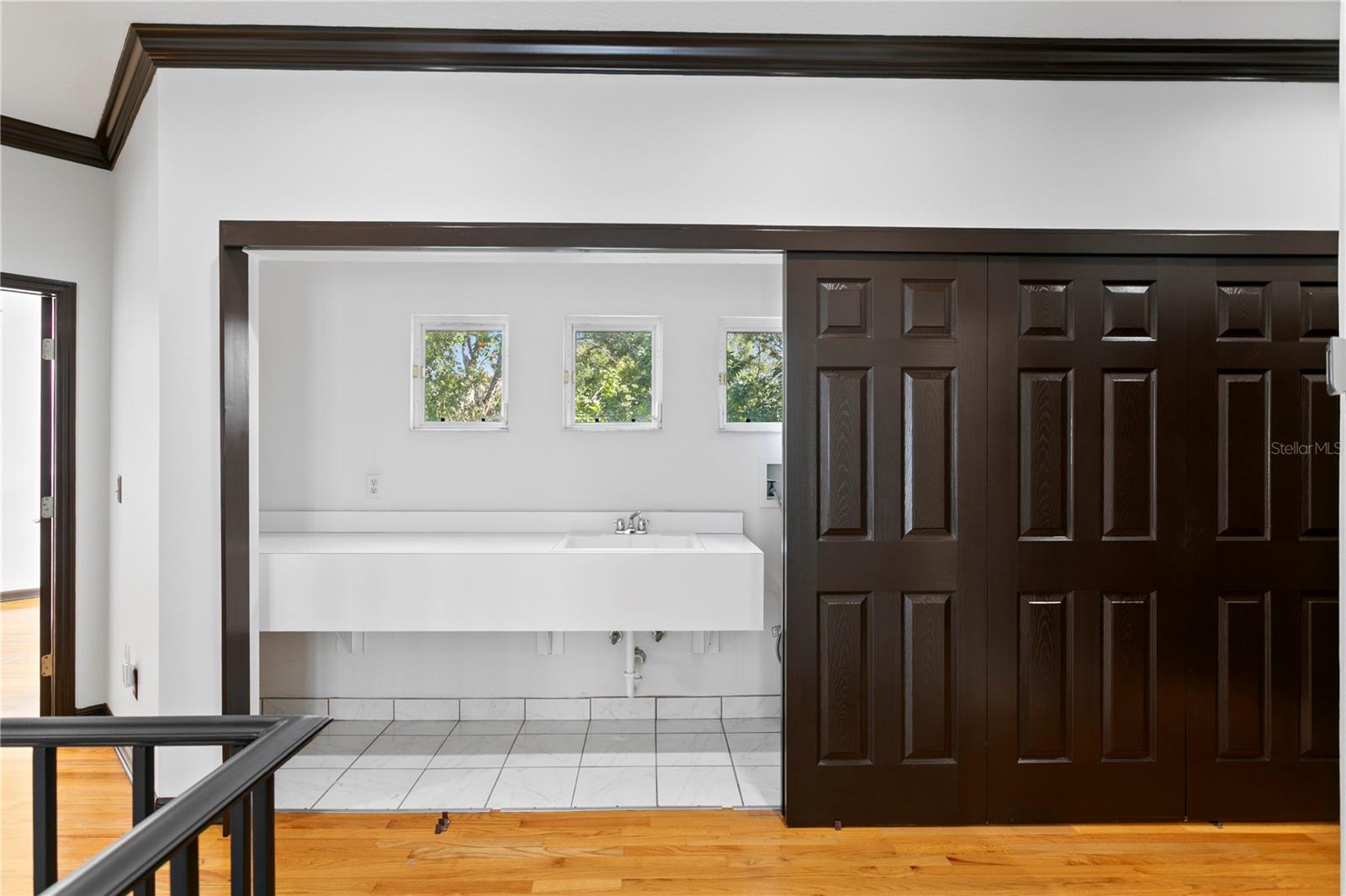 A dedicated folding area is tucked neatly behind sleek closet doors. This thoughtful design maximizes space and keeps laundry essentials out of sight for a streamlined look.