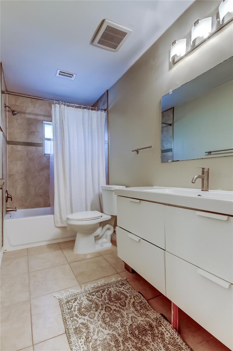 Hall bathroom with tub and floating sink.