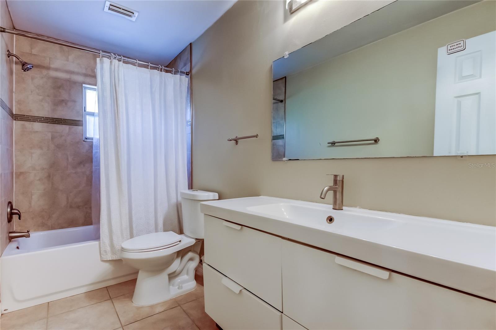 Another view of hall bathroom with tub and floating sink.