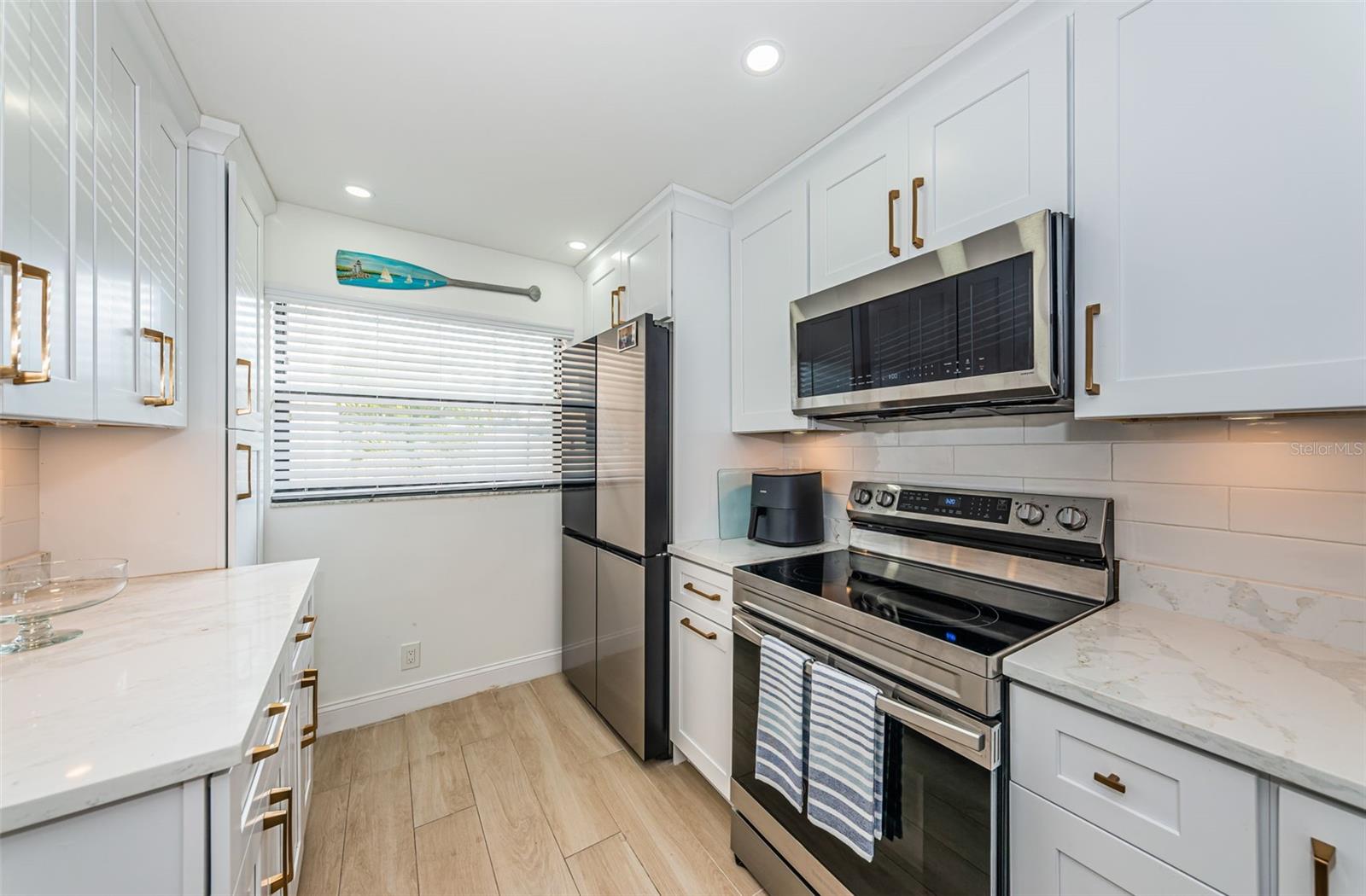 Kitchen has white cabinetry with quartz countertops