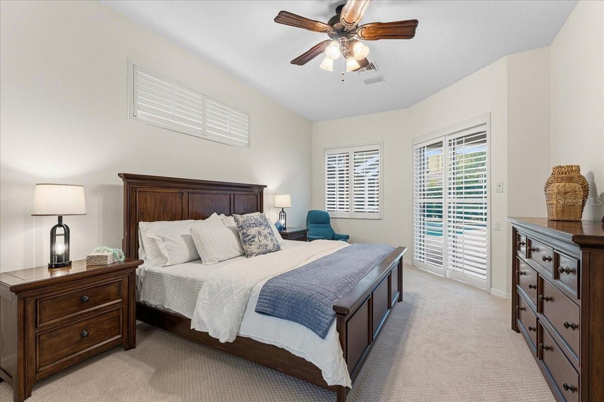 Primary Bedroom suite with shutters and sliders to pool
