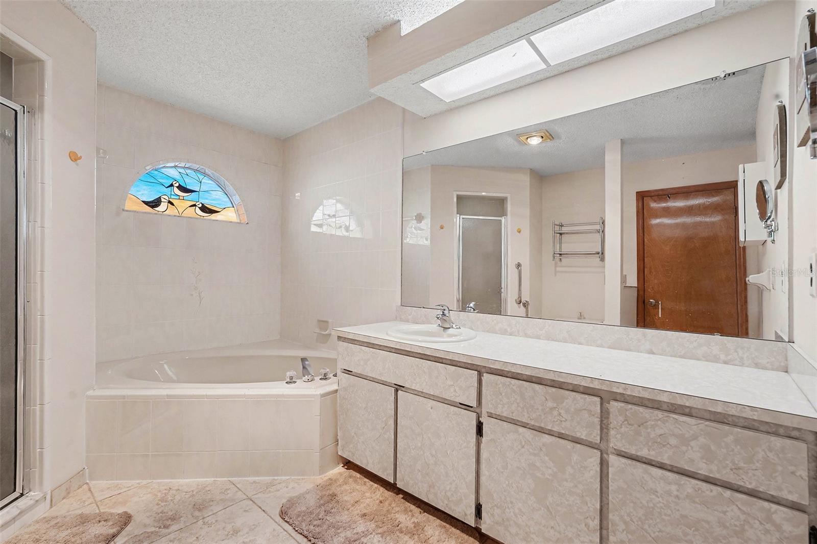 Main bathroom with custom stained glass window, jet tub, stand up shower