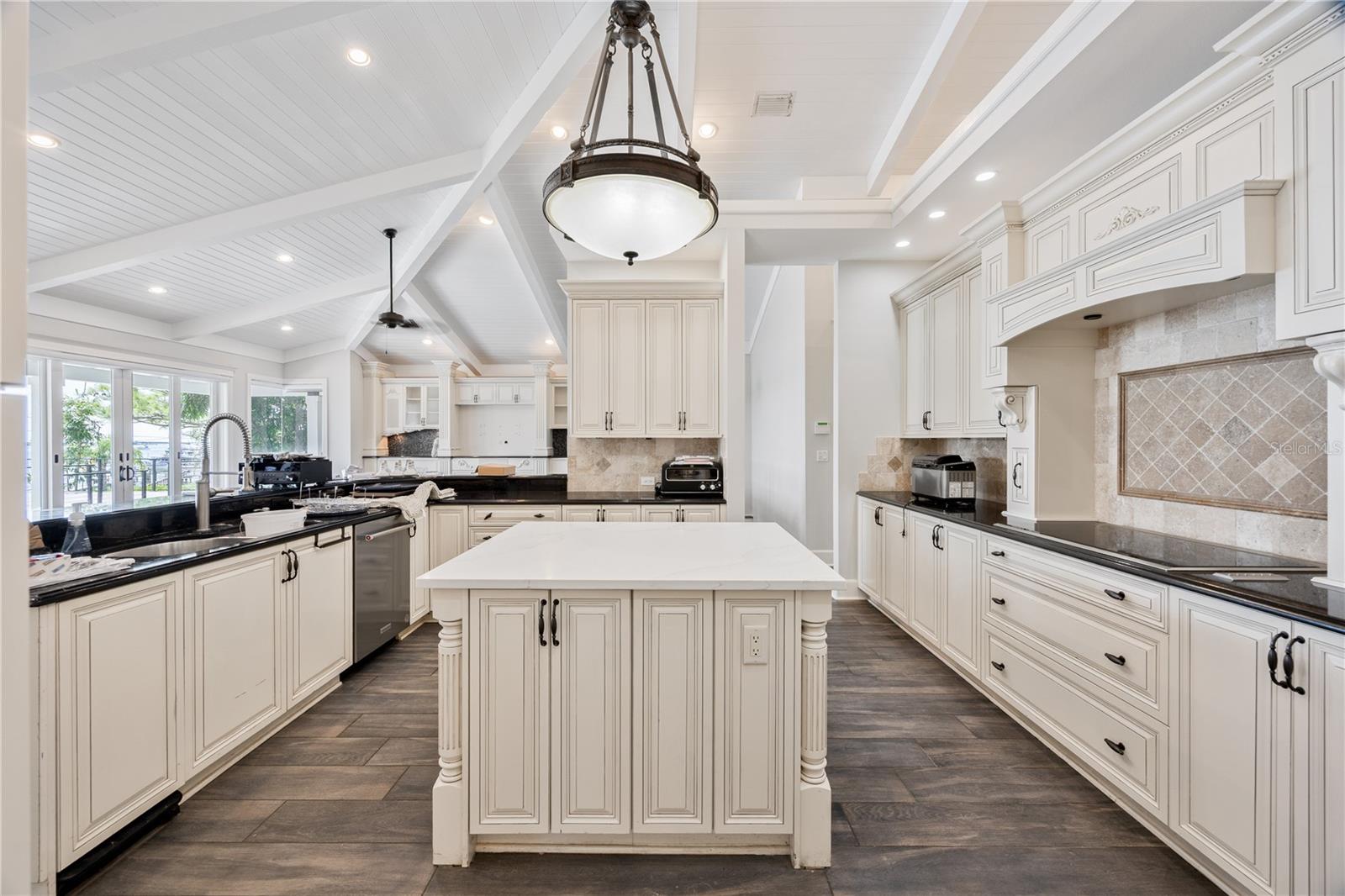 Luxurious designer kitchen showcasing custom cabinetry, exotic granite, wine cooler, and elegant architectural details.
