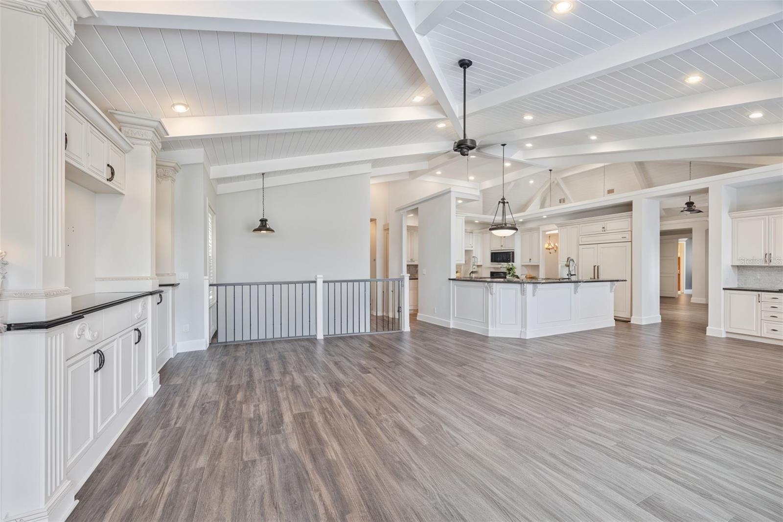 Expansive open family room showcasing vaulted ceilings, large windows, and a bright connection to the gourmet kithcen.