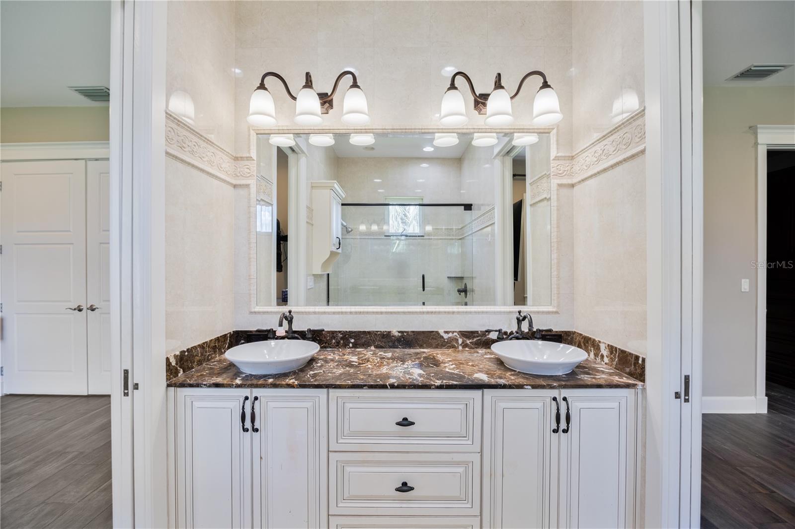Beautiful jack-and-Jill bath featuring dual vanities and updated stone countertops.