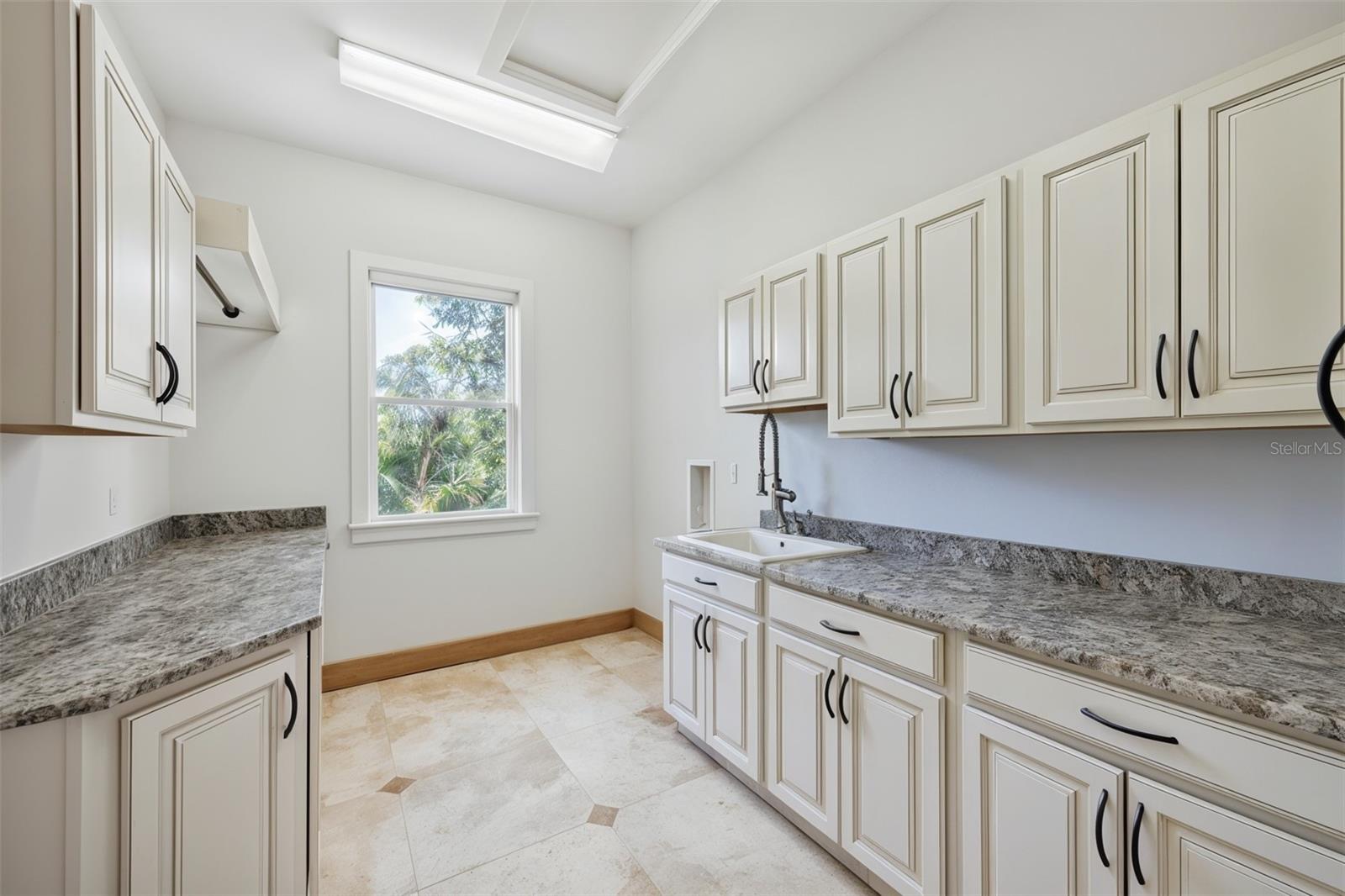 Spacious laundry room with abundant cabinetry and ample countertop workspace.