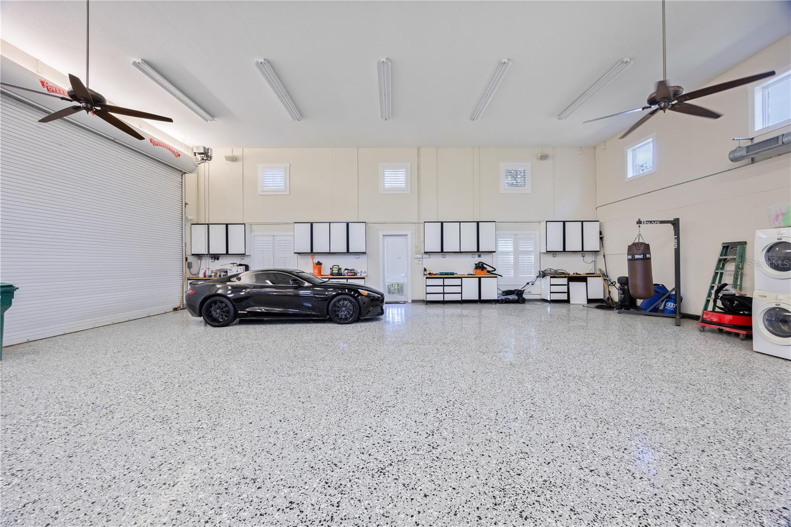 Bright spacious garage interior featuring epoxy flooring, soaring ceilings, and room for multipole vehicles, RV storage, and workshop equipment.