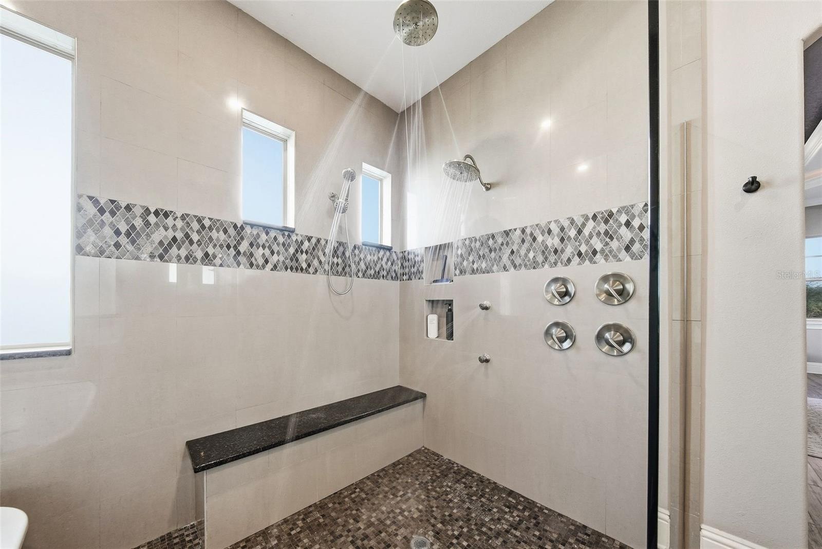 Shower has a rain shower and massaging sprays