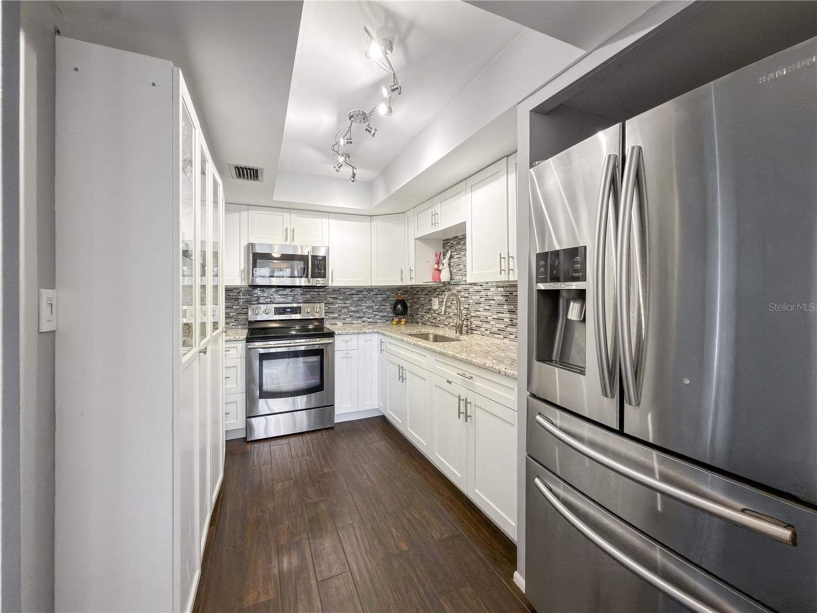 Kitchen Features Granite Countertops and a Matching Glass Mosaic Backsplash