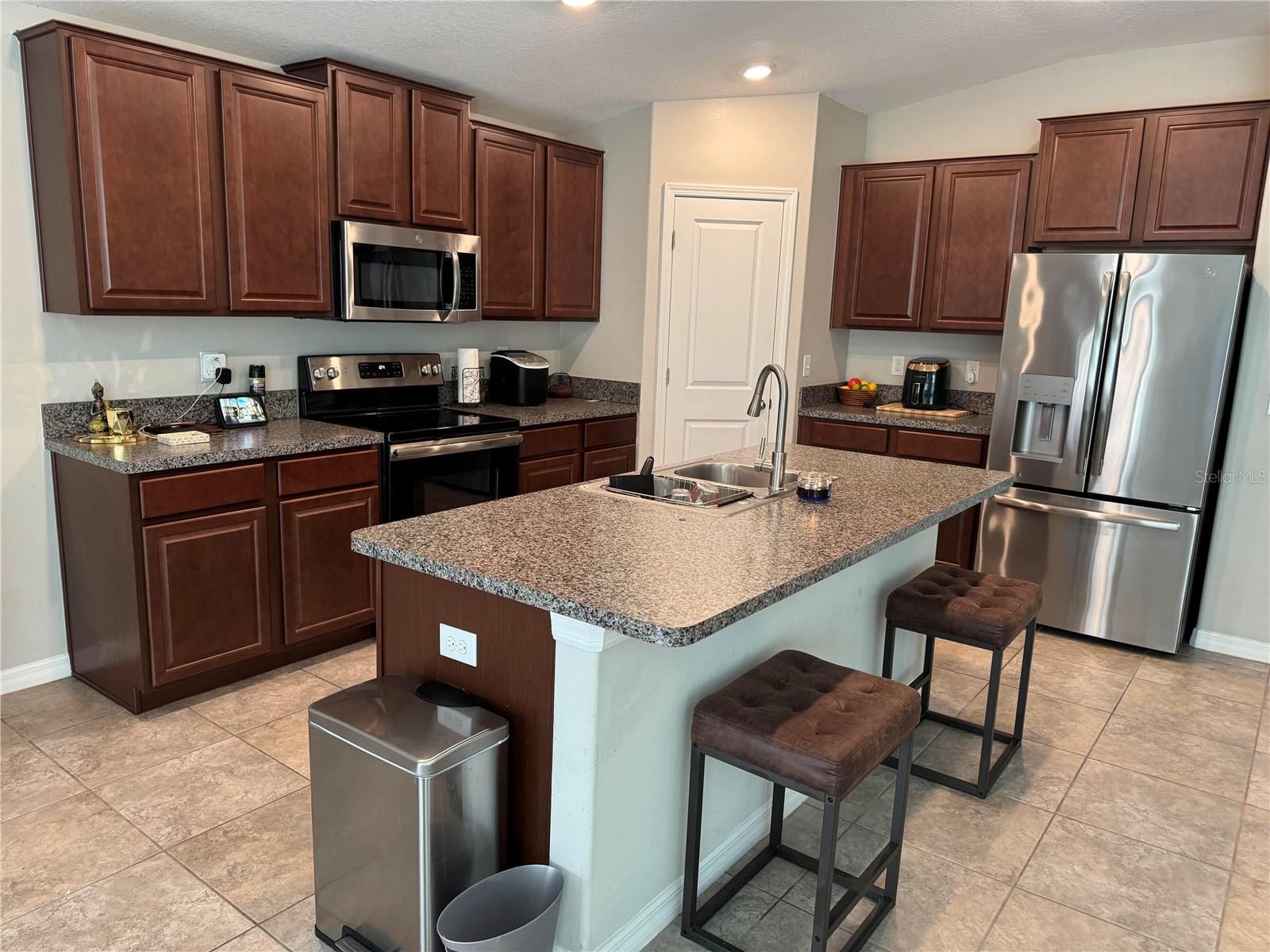 Comfortable kitchen with stone countertops and wood cabinets.