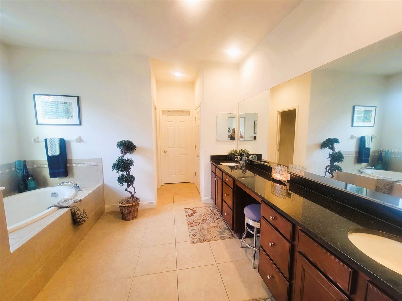 featuring a double-sink vanity, soaking tub, separate glass-enclosed shower, and ample storage—designed for comfort and relaxation.