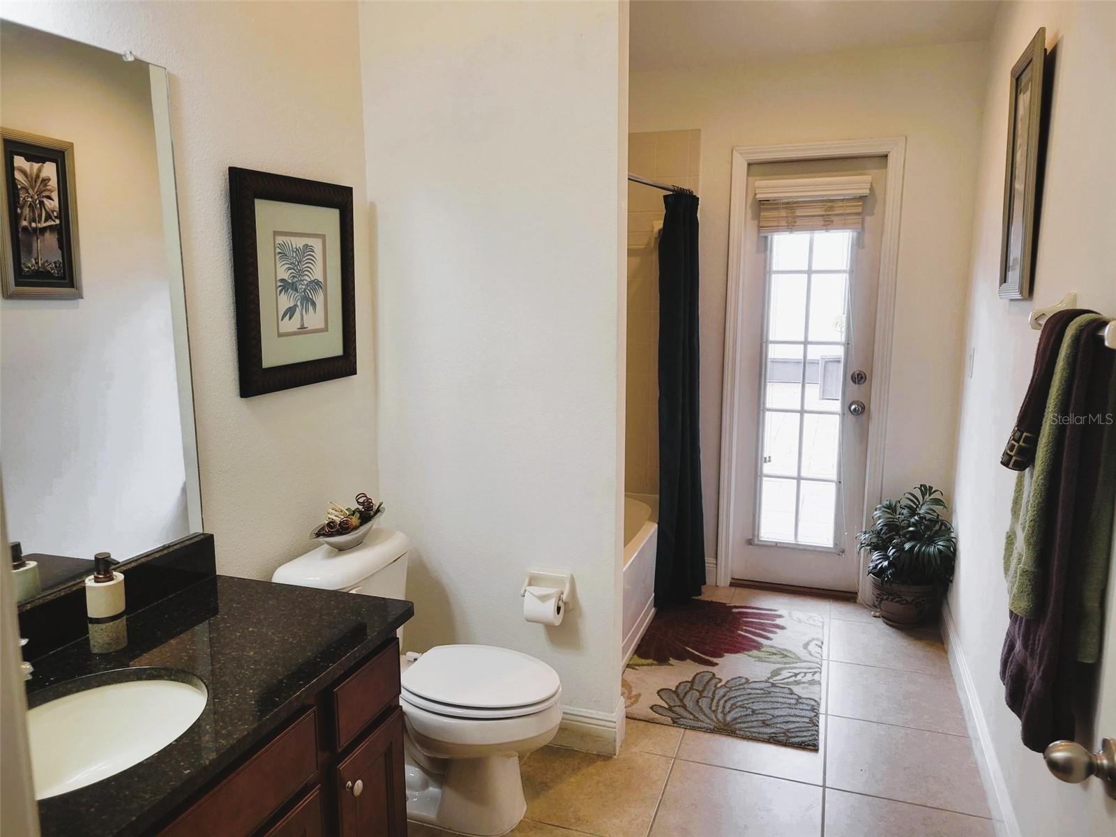 Convenient pool bath with granite vanity and direct access to the lanai—ideal for entertaining and easy outdoor living without tracking through the home.