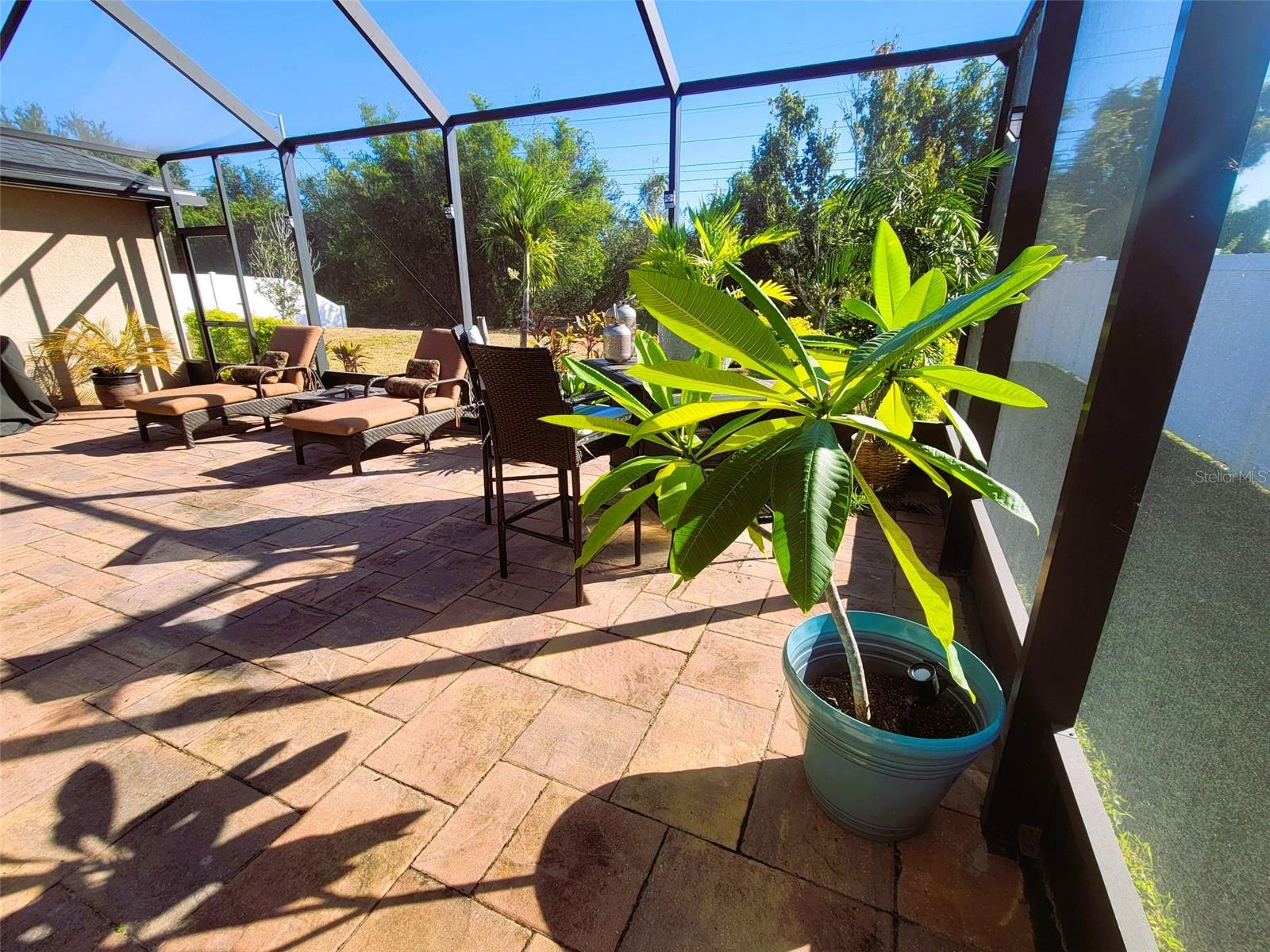 Expansive 28’ x 20’ screened lanai with paver flooring, overlooking a private conservation homesite and featuring a convenient door to the backyard—ideal for outdoor living and entertaining.