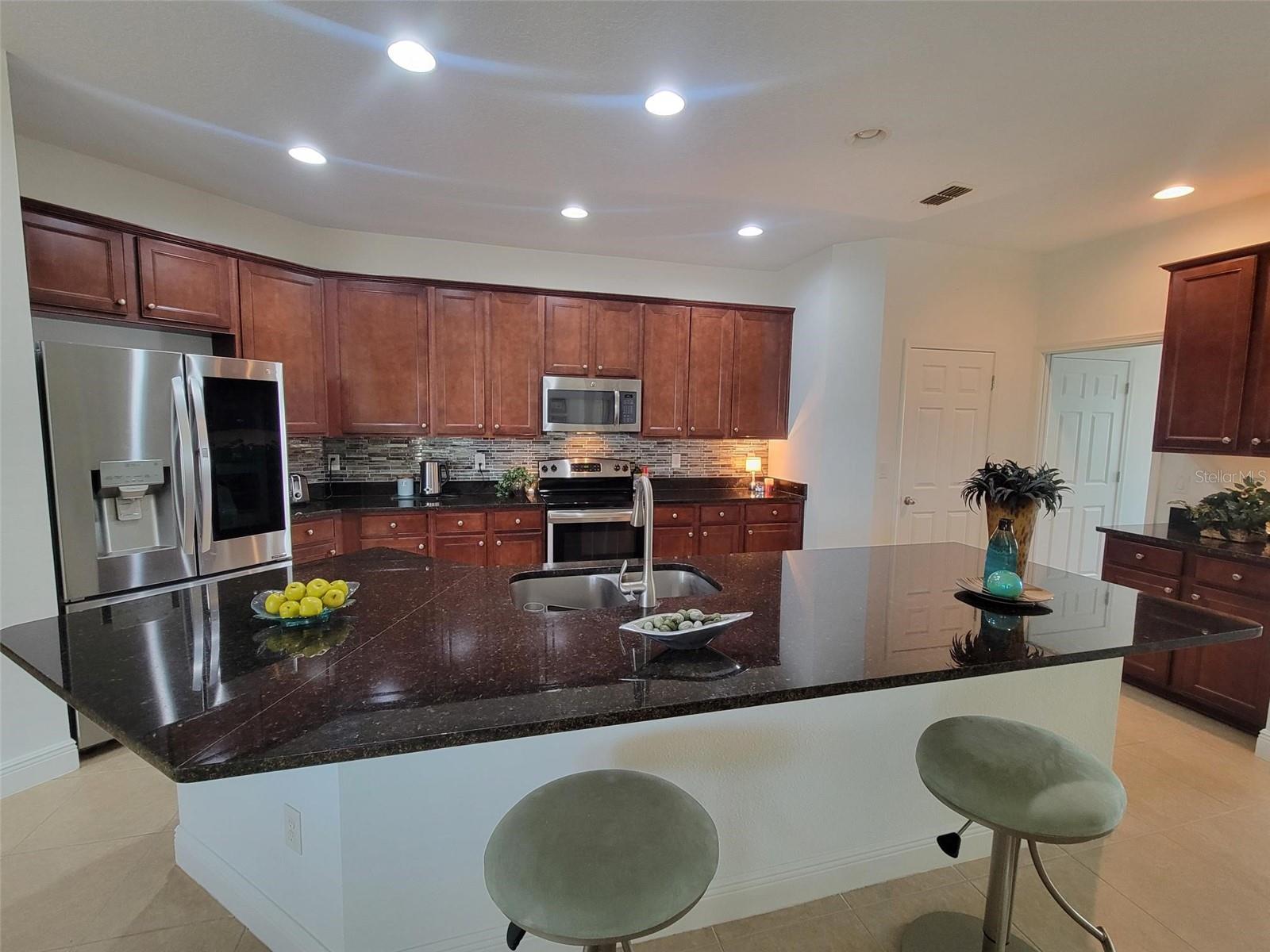 Spacious kitchen featuring an oversized island, granite countertops, and seating—ideal for entertaining.