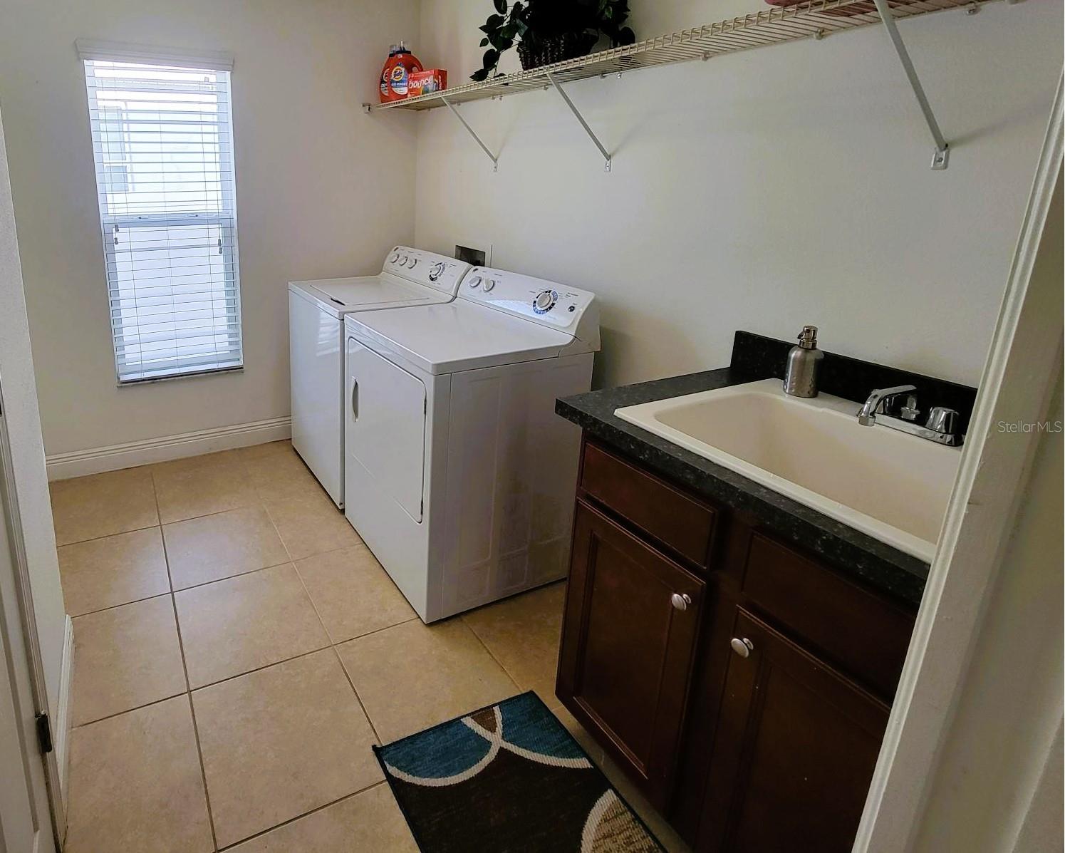 Spacious laundry room with utility sink, storage shelving, and direct access to the 3-car garage.