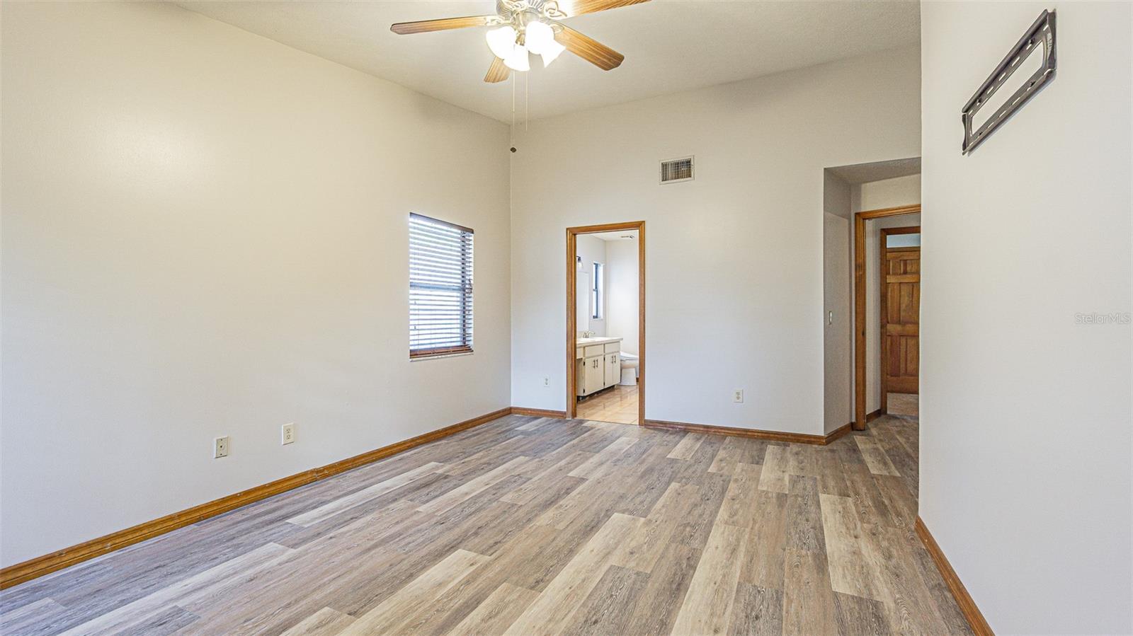 Primary bedroom looking from back wall into entry and ensuite bath (walk-in closet is just inside the bathroom door)