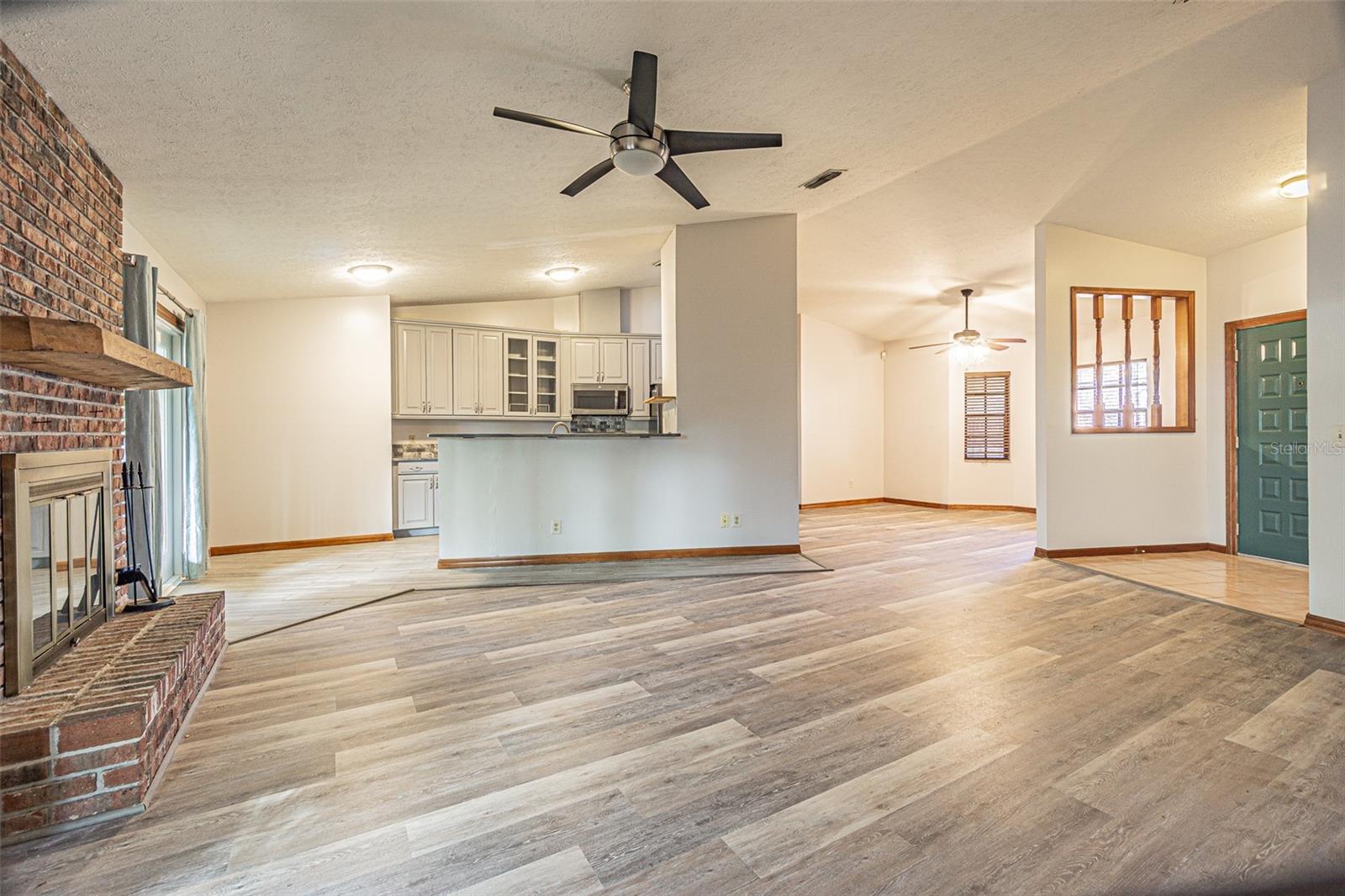 Open floorplan viewing living room, kitchen, dining room and entryway