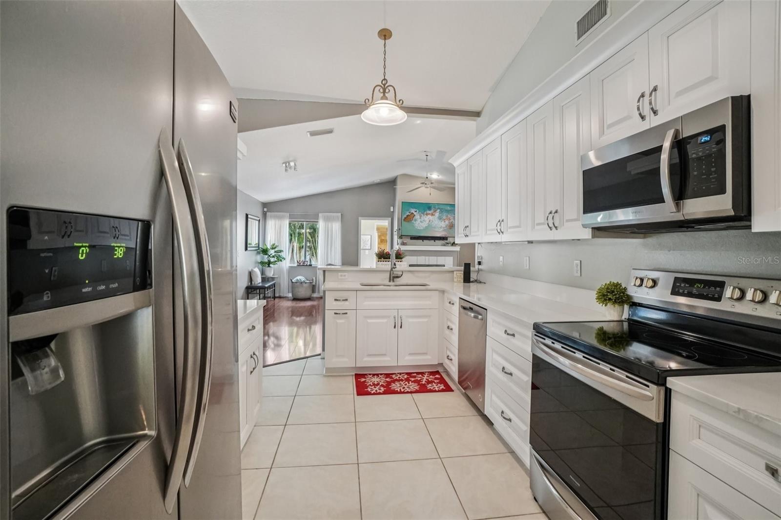 Kitchen (View Toward Living Area) – This bright, updated kitchen features white cabinetry, stainless steel appliances, and tile flooring, with a functional layout that opens seamlessly to the main living spaces.