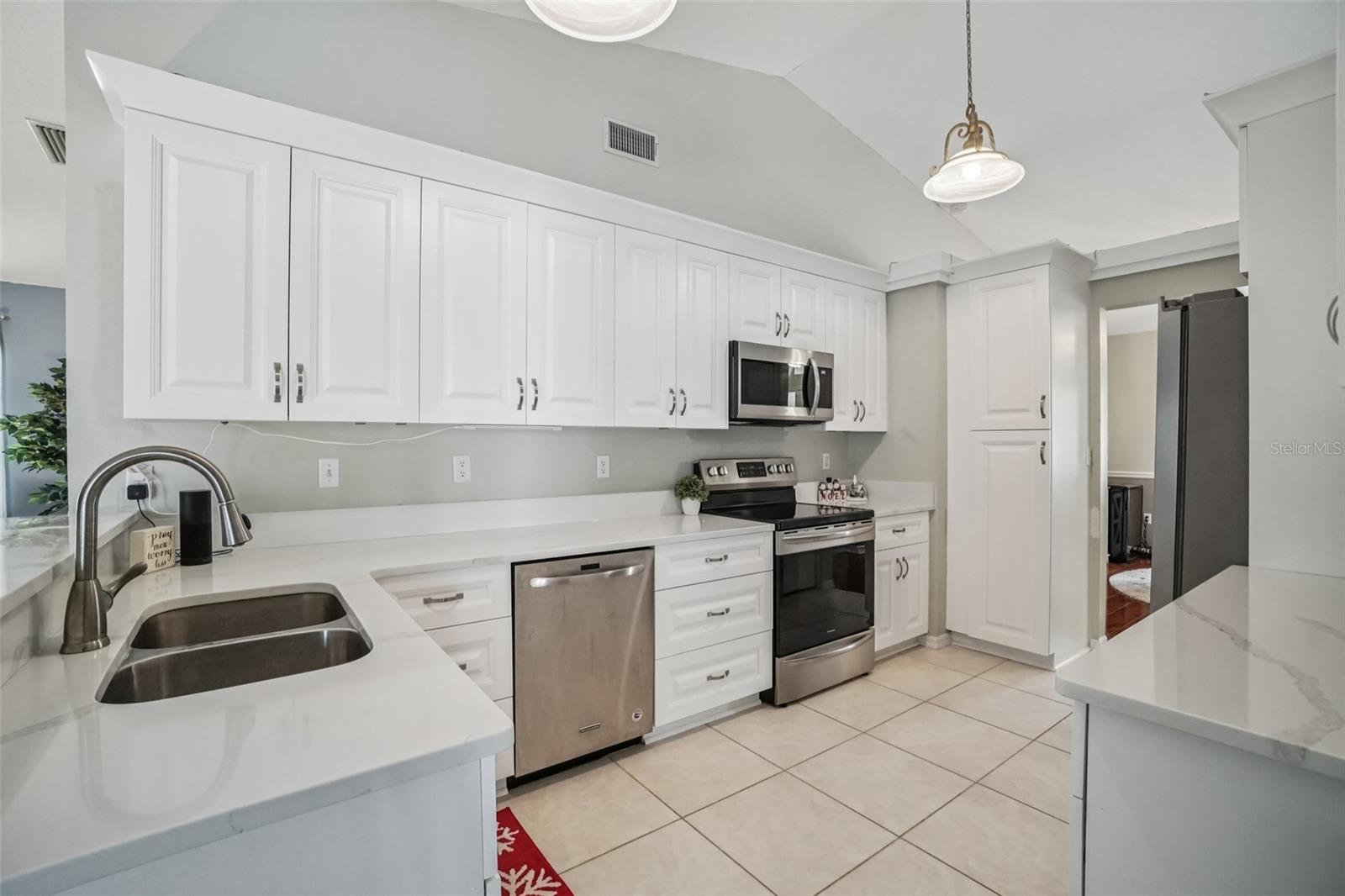 Kitchen (Cabinetry & Appliance Detail) – Crisp white cabinets extend to the ceiling, paired with sleek countertops and stainless steel appliances for a polished, cohesive look.