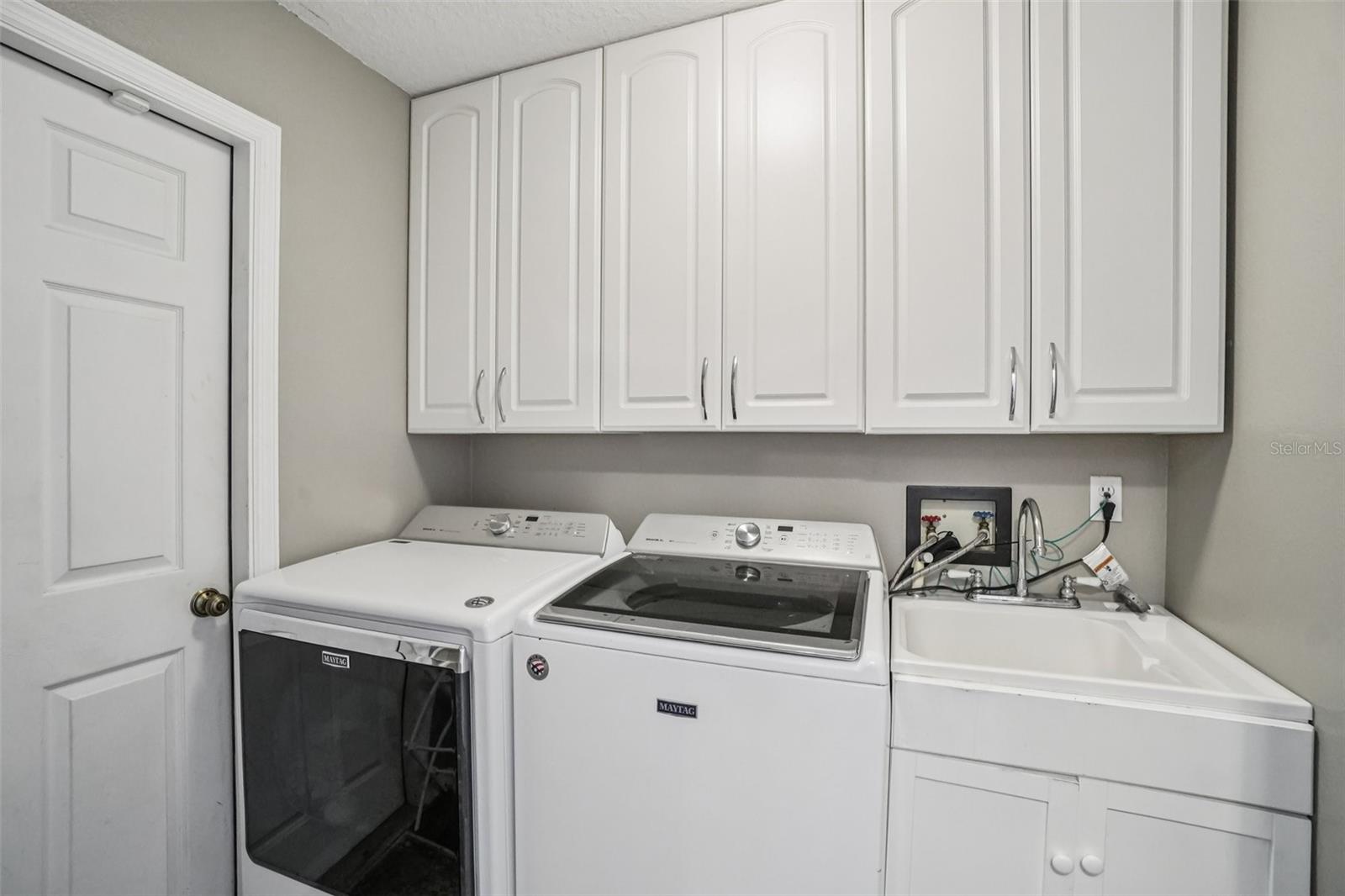 Laundry RoomDedicated laundry room featuring full-size washer and dryer, utility sink, and ample overhead cabinetry for organized storage and everyday convenience.