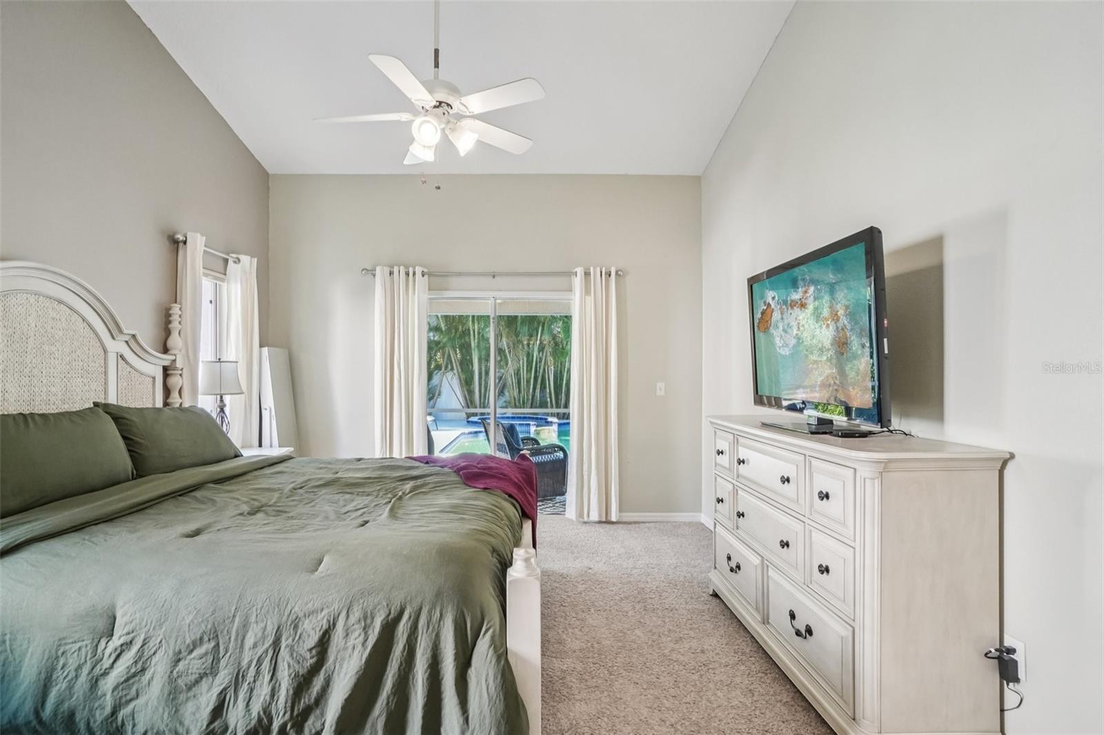 Primary Bedroom – Alternate AngleAn additional view of the primary bedroom highlights generous space for a full furniture set, soft carpeting, and tranquil views of the backyard oasis.