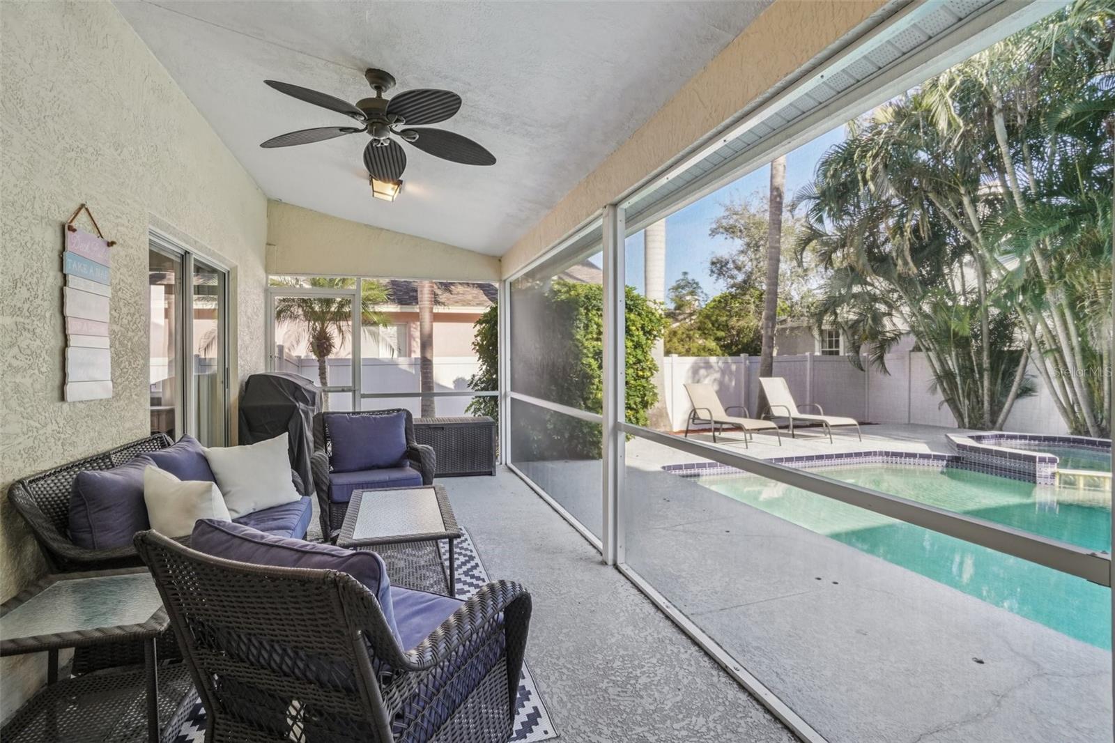 Covered Screened Patio & Pool ViewRelax and entertain in the covered, screened patio featuring ceiling fan, comfortable seating area, and serene views of the private pool and tropical landscaping—perfect for year-round Florida living.