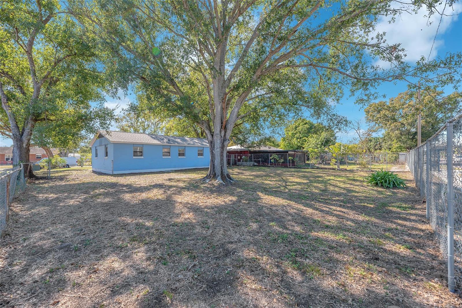 A large, partially fenced backyard with a beautiful shade tree provides the perfect space for pets, entertaining, or future outdoor enhancements.