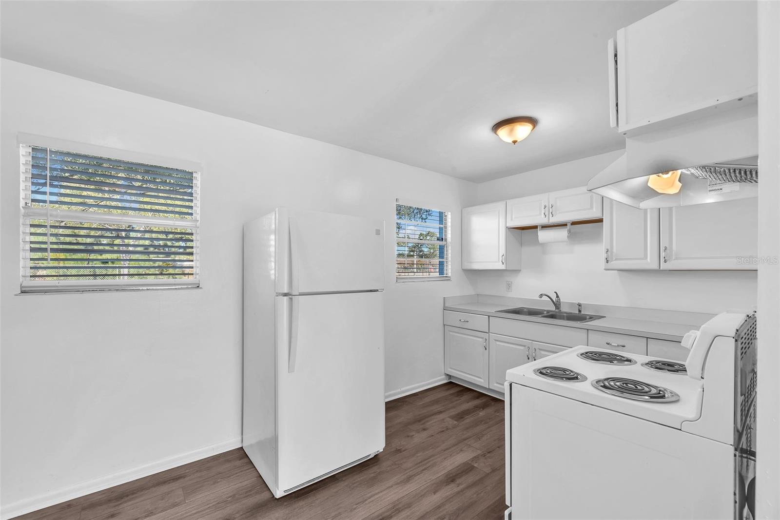The cozy kitchen features classic white cabinetry and white appliances, creating a bright, clean space that feels fresh and functional.