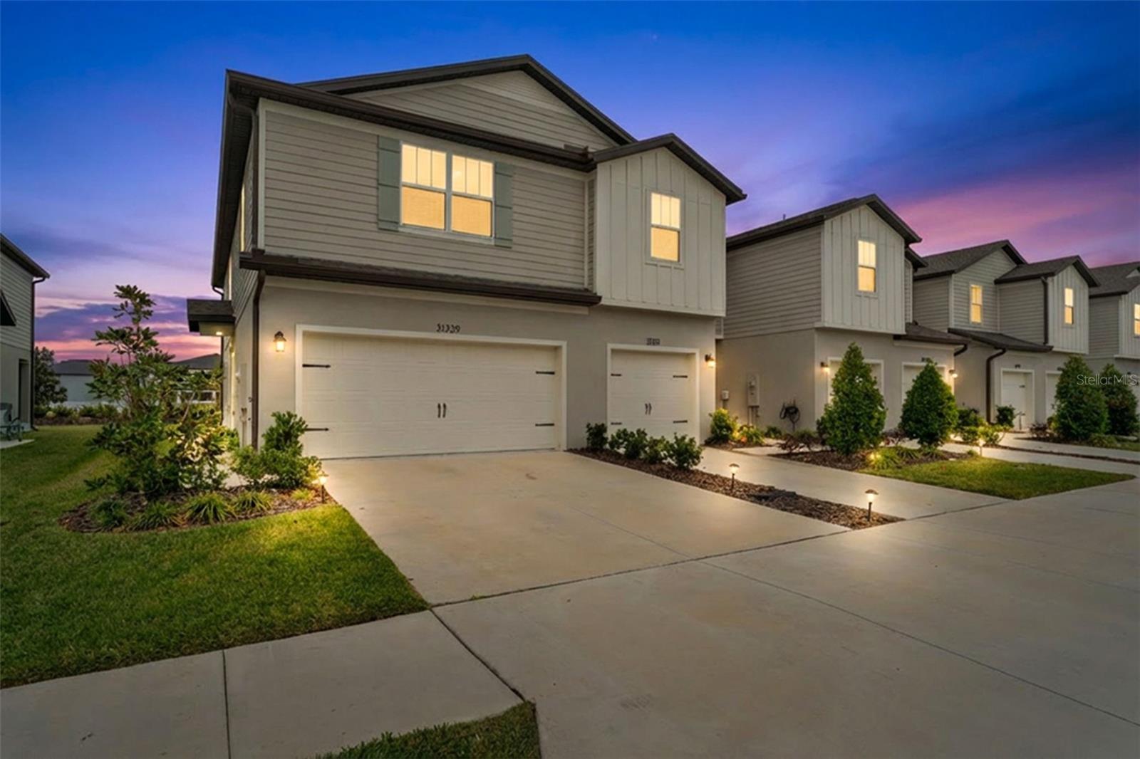 Modern townhouse exterior with a two-car garage, clean architectural lines, and soft evening lighting that highlights the home’s curb appeal.