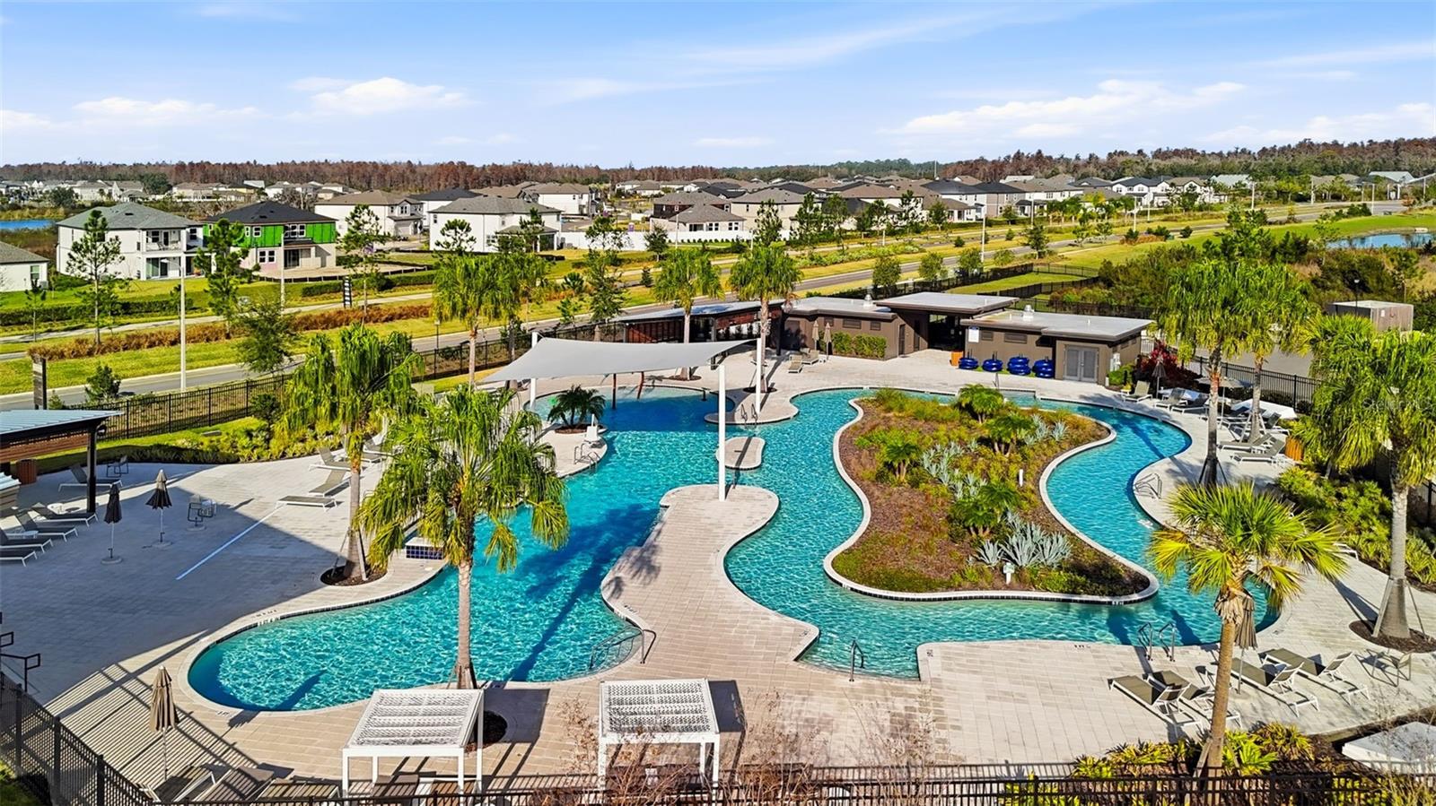 xpansive community pool with winding waterways, multiple lounging areas, and tropical landscaping, creating a true resort atmosphere.
