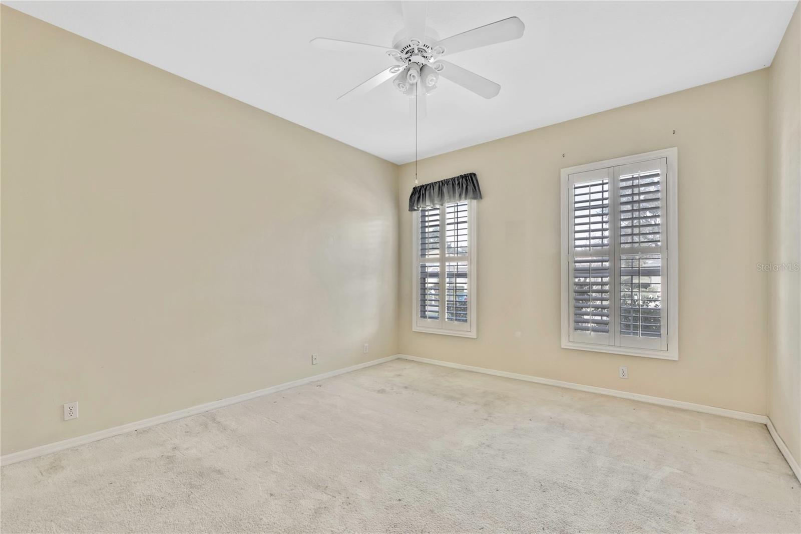 At 12' x 15', bedroom 2 has neutral carpet, wall color and plantation shutters. it can be considered a second primary suite with 2nd bath just outside the door.
