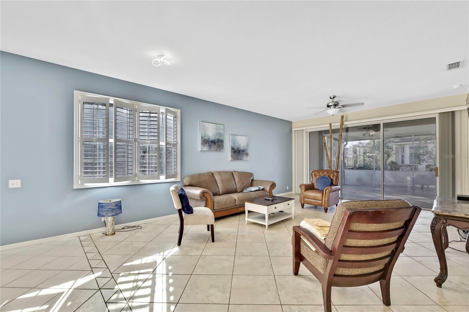 Through the foyer, is the living room that receives ample light, featuring neutral designer colors and plantation shutters.