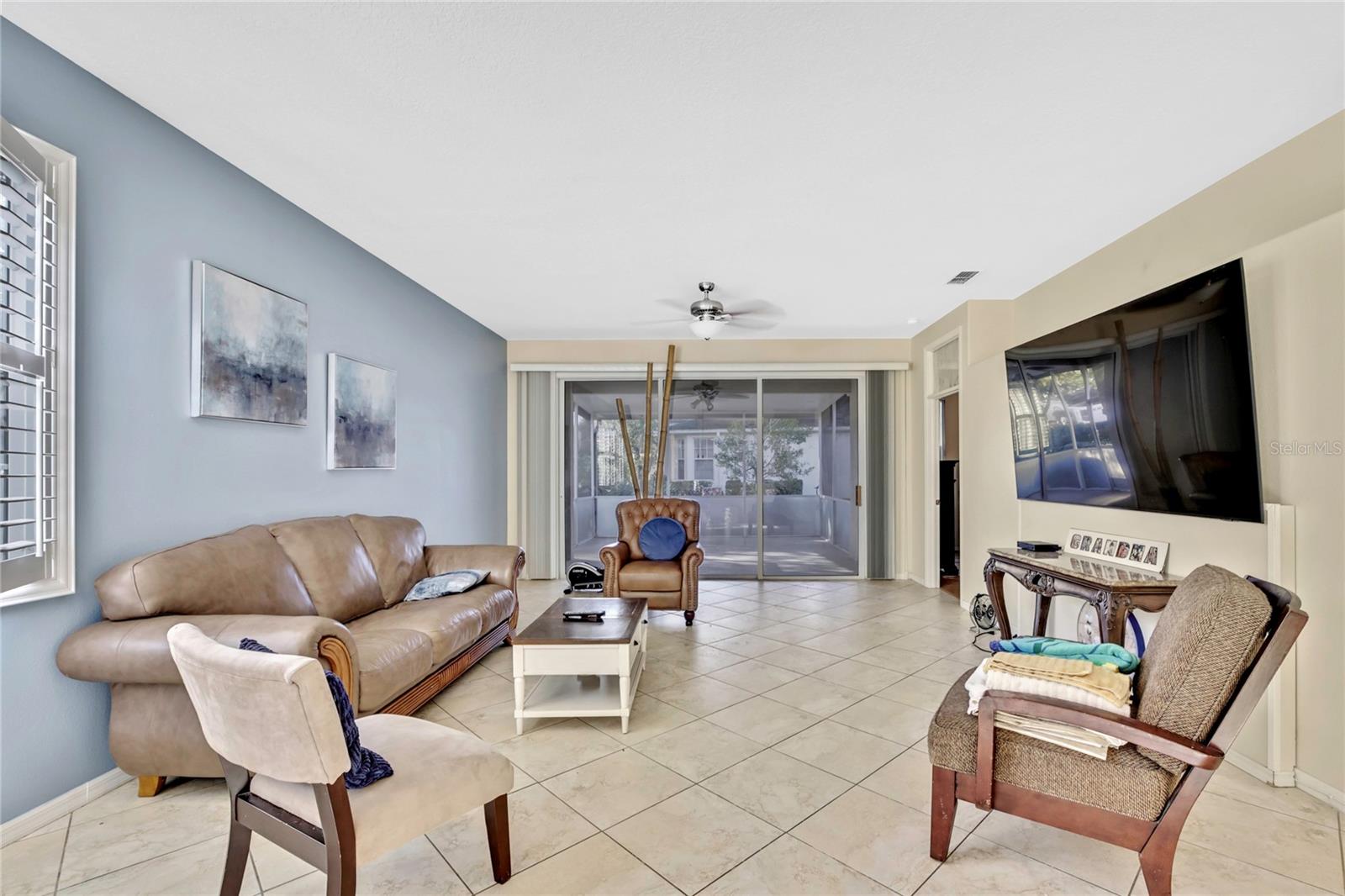 Beyond the living room, through new double-paned sliding doors, lies a spacious, covered, and screened-in porch.