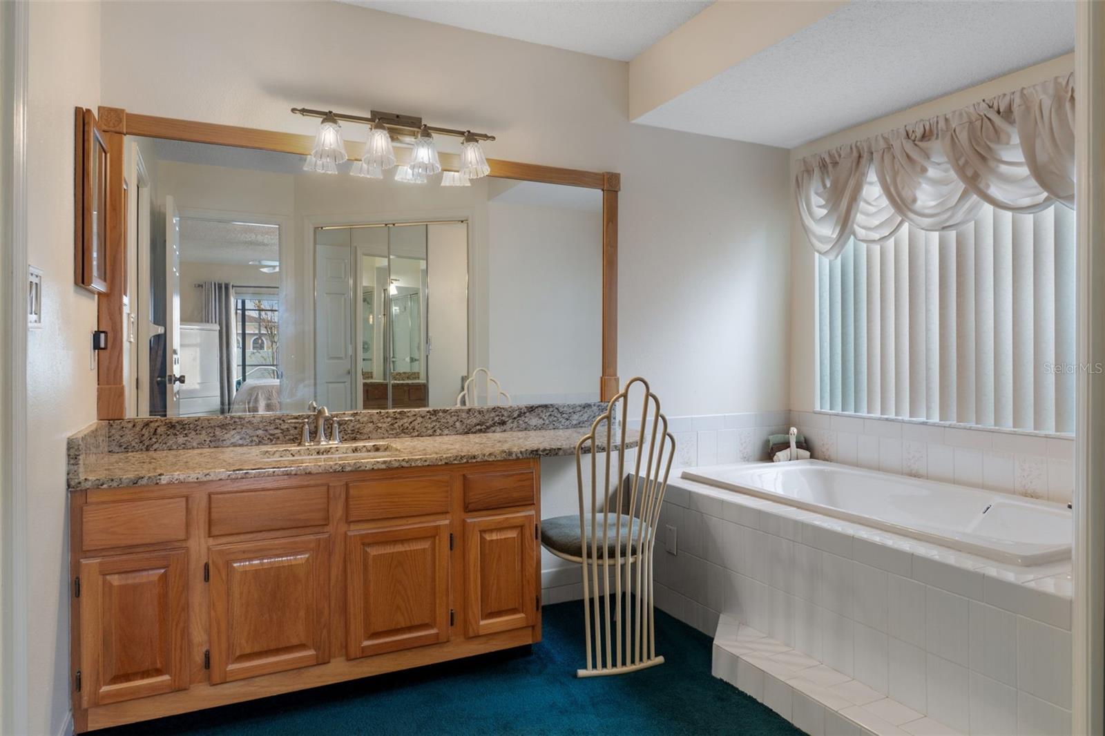 Primary bathroom/dressing area boasts a beauty bar, upgraded cabinets, granite countertops and a soaking tub.