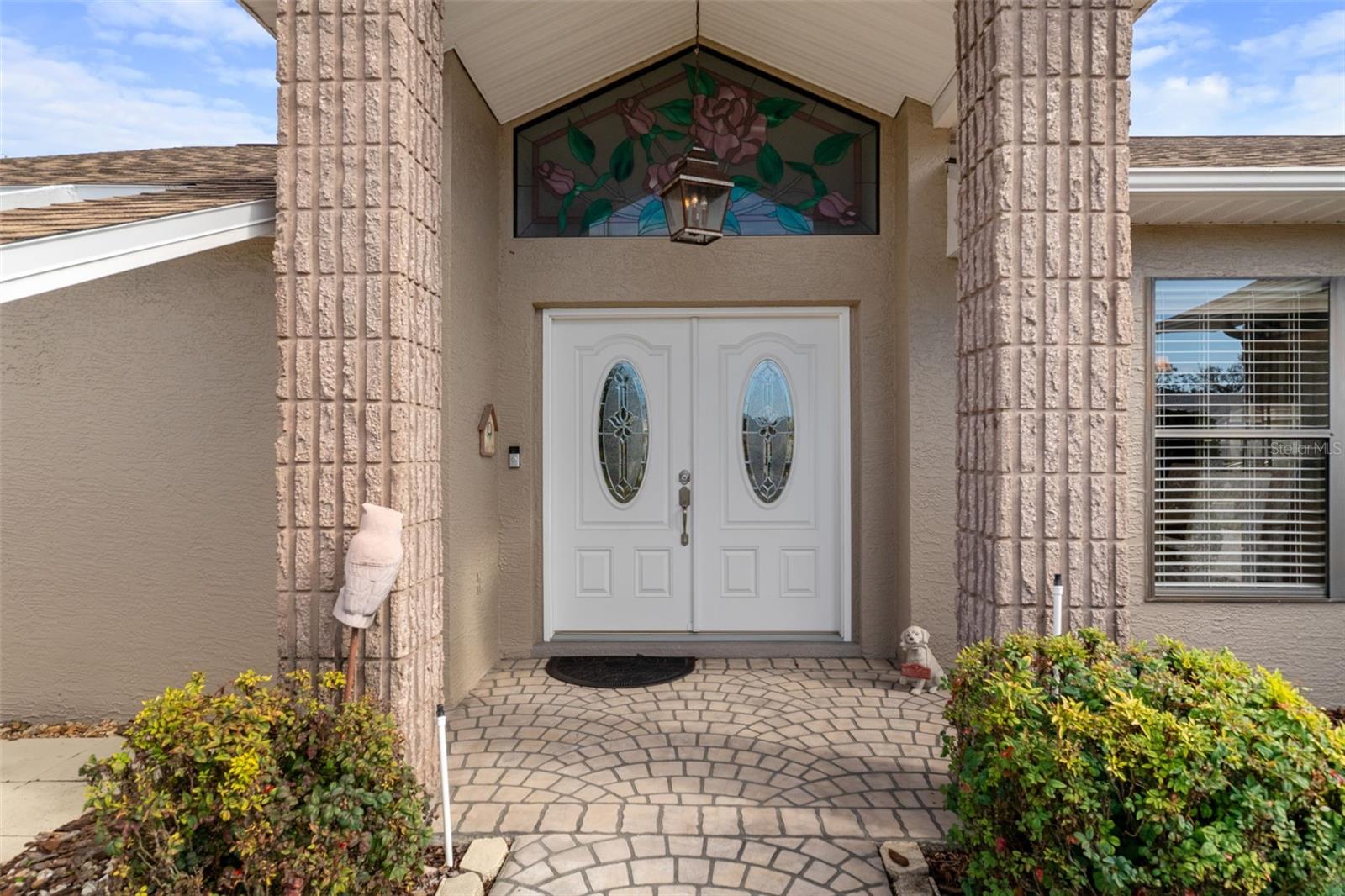 Beautiful glass inlay double door entry with stained glass window above.