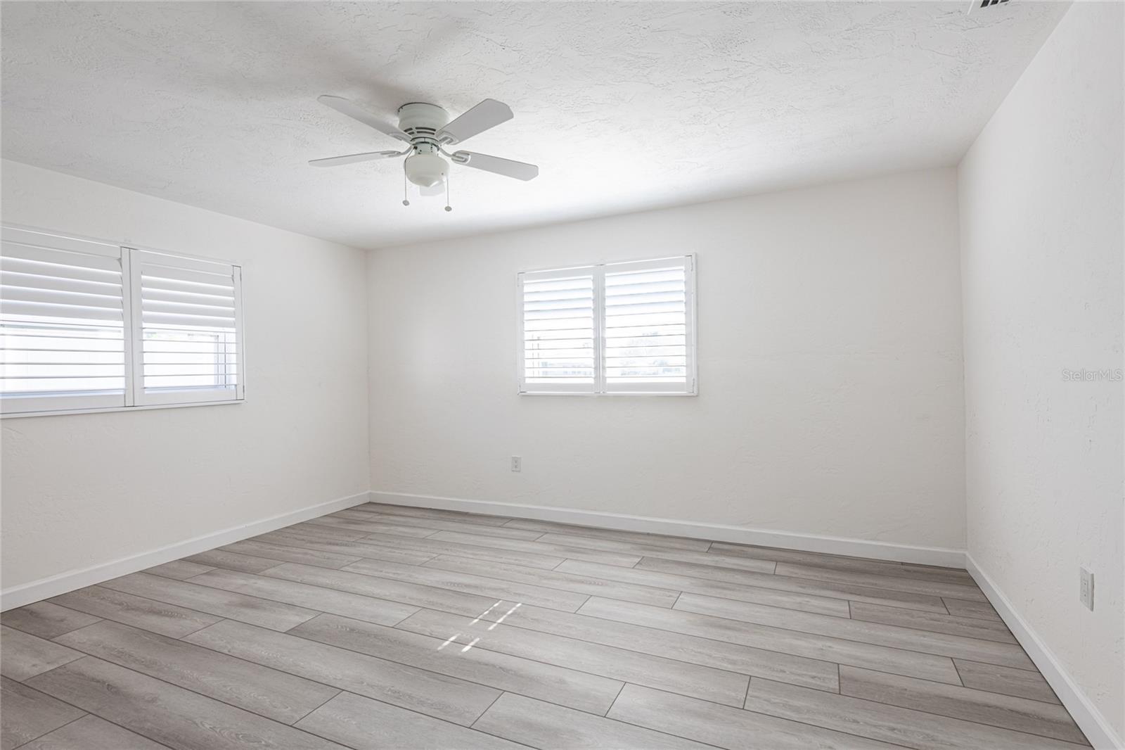 Primary bedroom with shutters overlooks back yard and water
