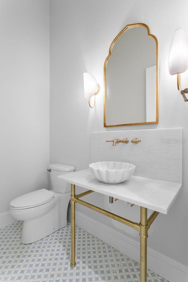 ELEGANT POWDER BATH WITH MARBLE COUNTER AND CARVED STONE SINK.