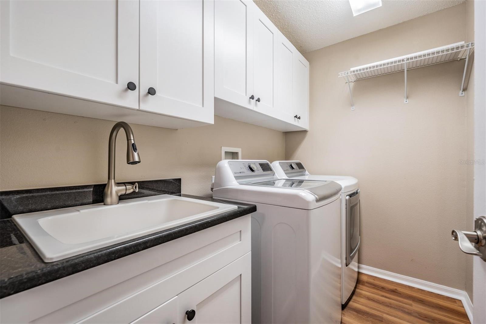 Walk-in laundry room with utility sink and additional storage