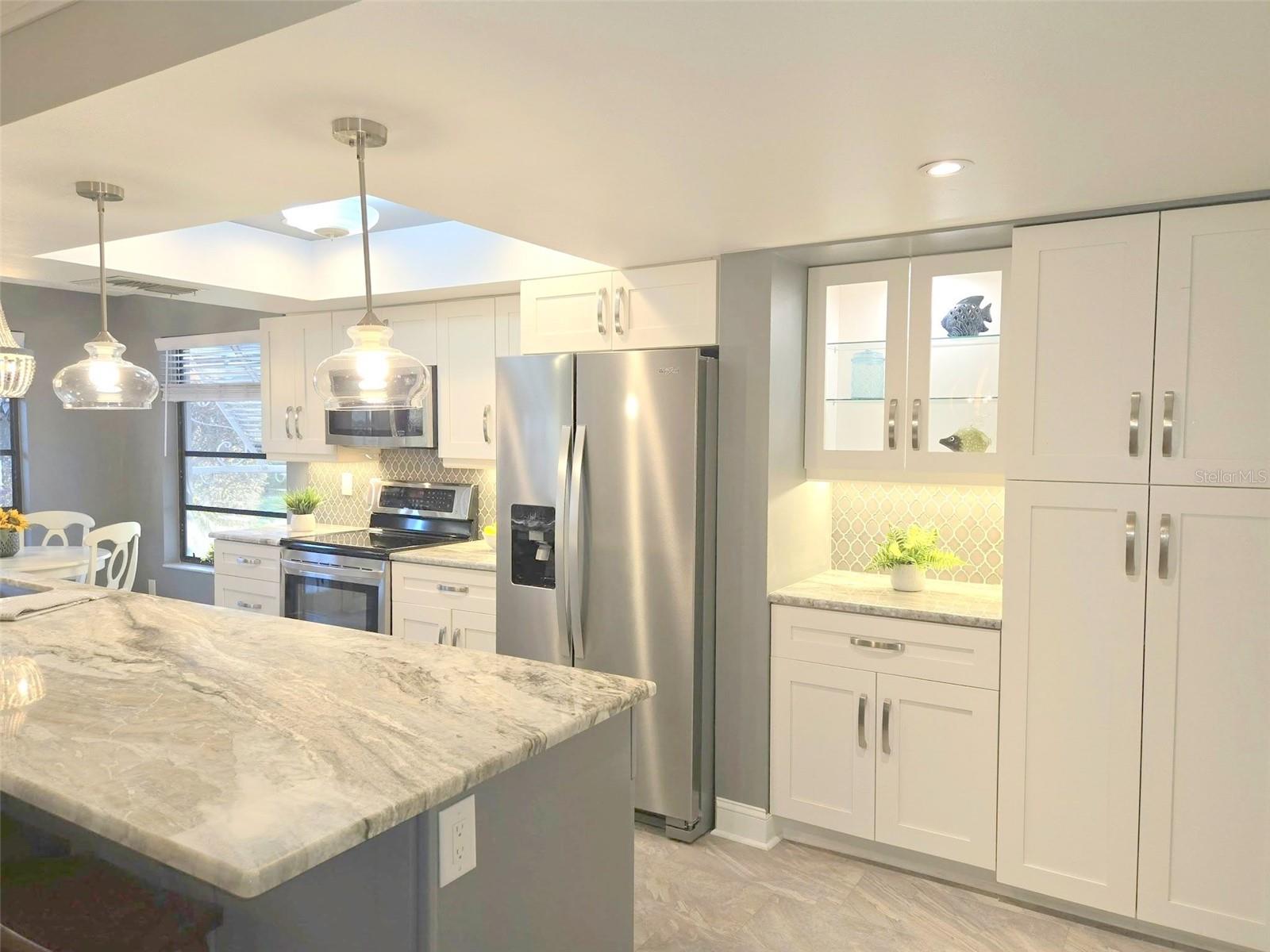 An artful kitchen with two tone wood cabinets topped with Fantasy granite & completed with coordinating Arabesque splash walls~