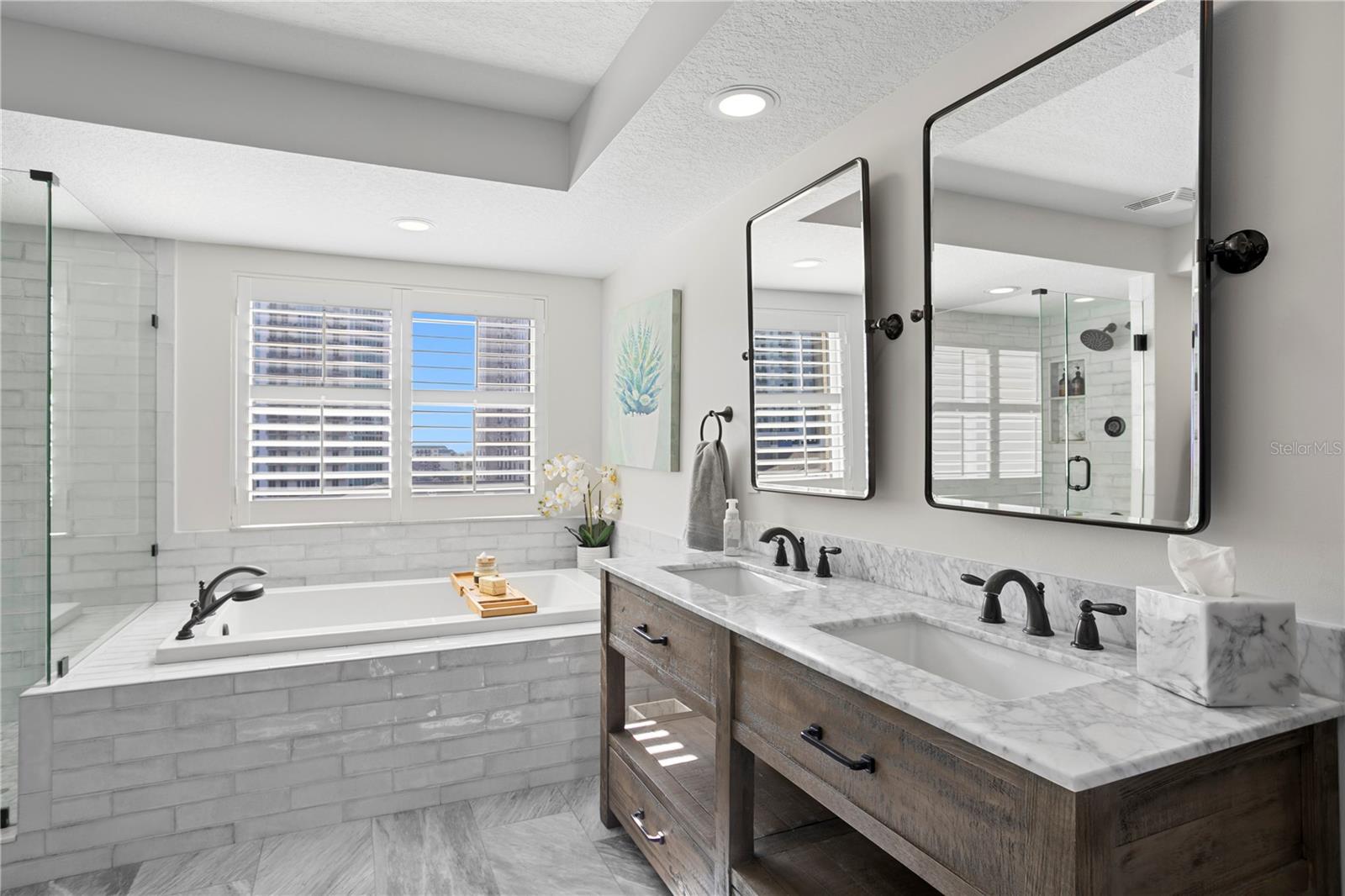 Fully reimagined primary bathroom showcasing a deep soaking tub, dual vanities, and an oversized walk-in shower.